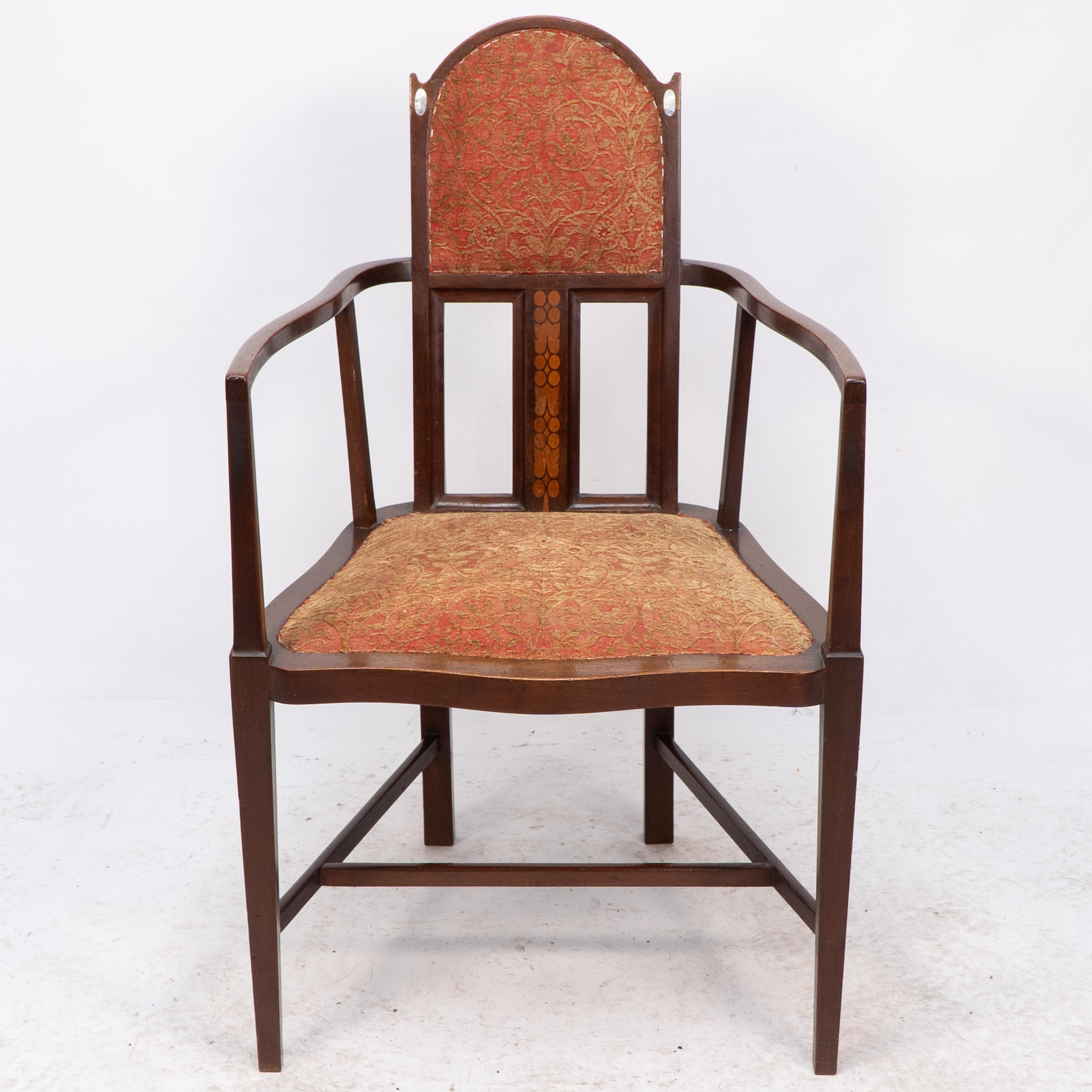 An armchair designed by George Montague Ellwood and made by J S Henry, with arched top and oval mother-of-pearl inlays just below the ears and sinuous arms with conforming seat details to the side and subtle curve to the front and extra