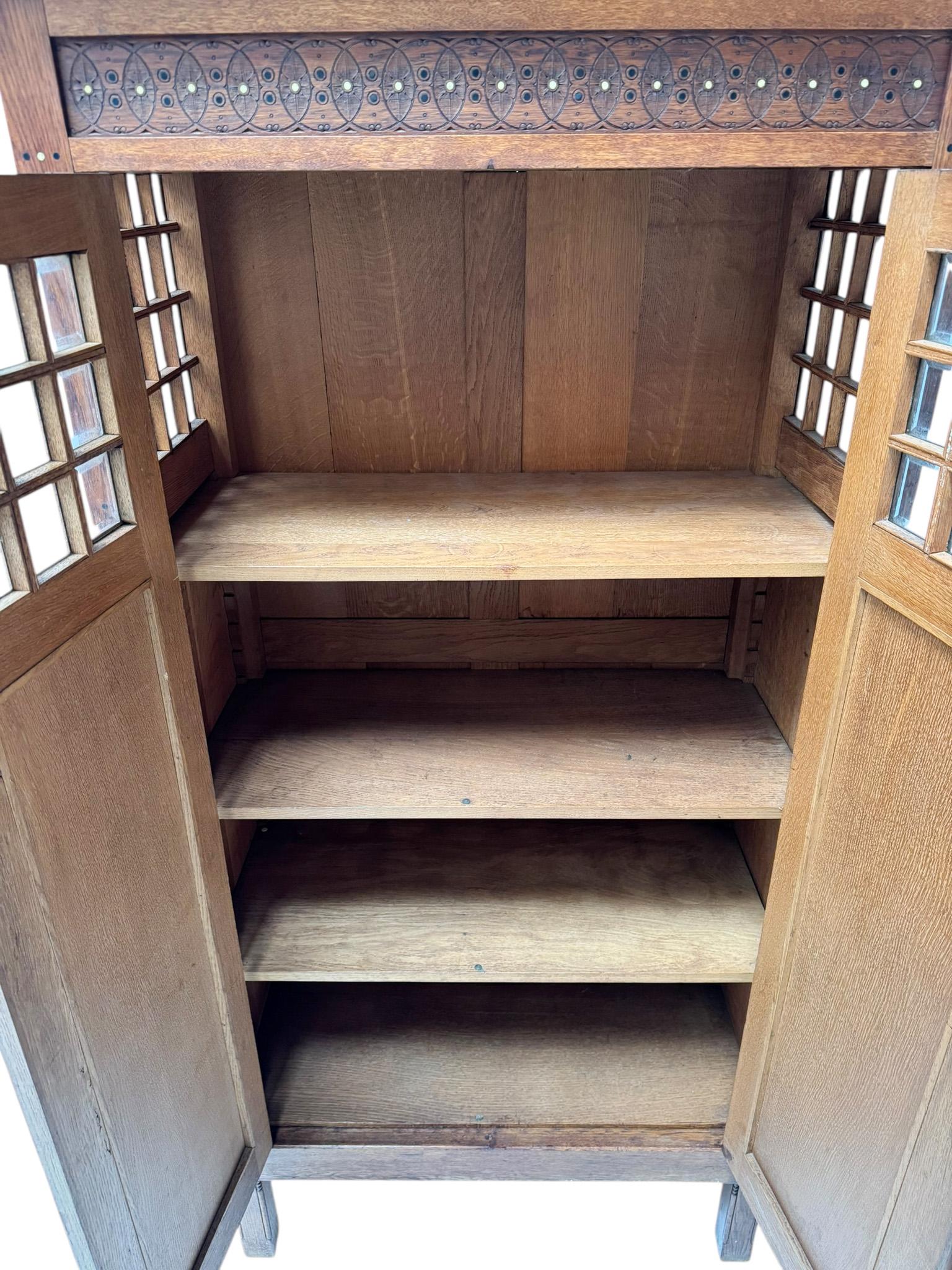 Magnificent and ultra rare Arts & Crafts armoire or bookcase.
Design in the style of Architects Lauweriks or K.P.C. de Bazel.
Striking Dutch design from the 1890s.
Solid oak base with various decorative elements an 50 original beveled glass elements