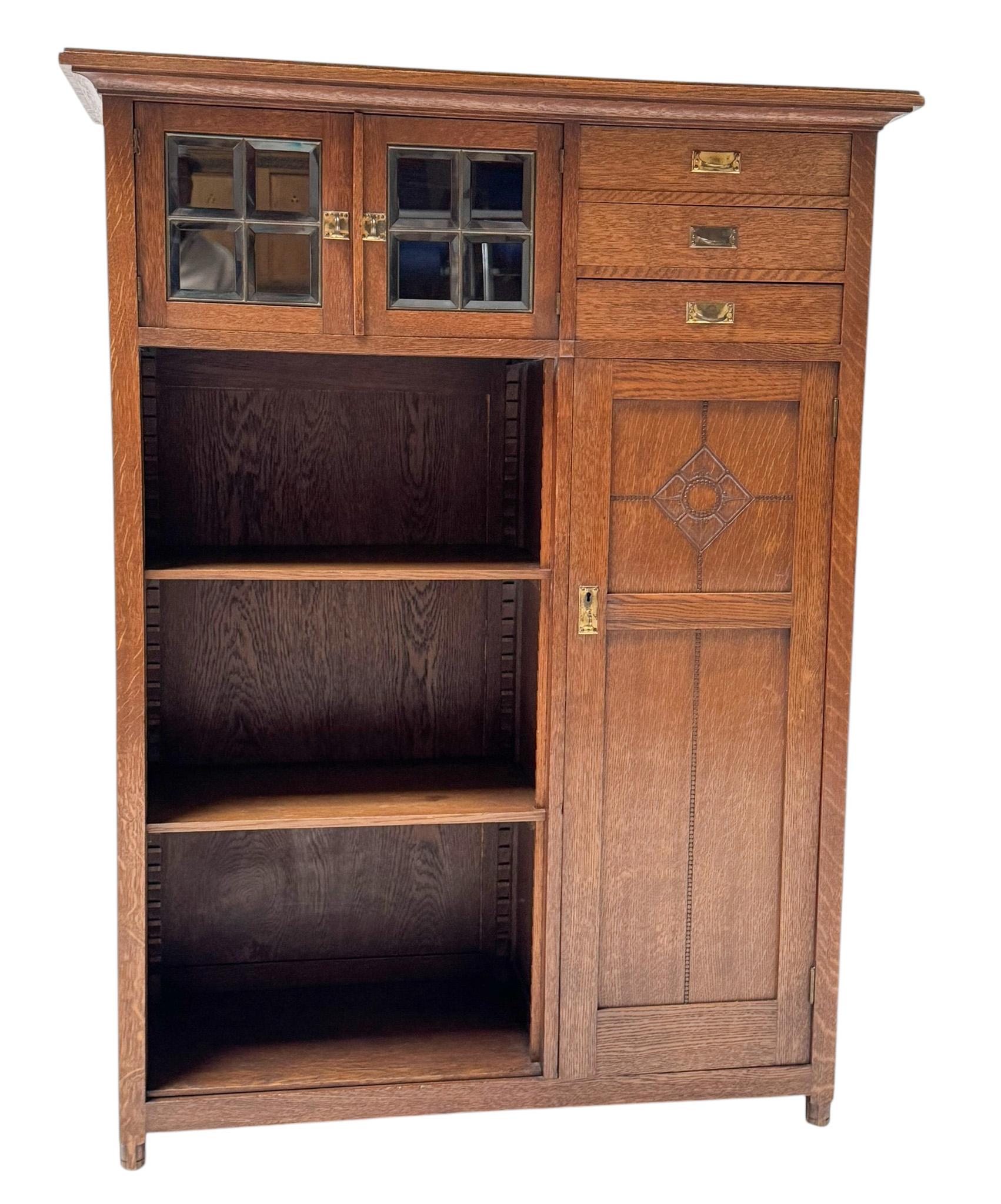 Magnificent and rare Arts & Crafts Art Nouveau bookcase.Design in the style of  Order den Sent Maarten.Striking Dutch design from the 1900s.Solid oak base with two small doors with original beveled glass and original brass handles, three drawers