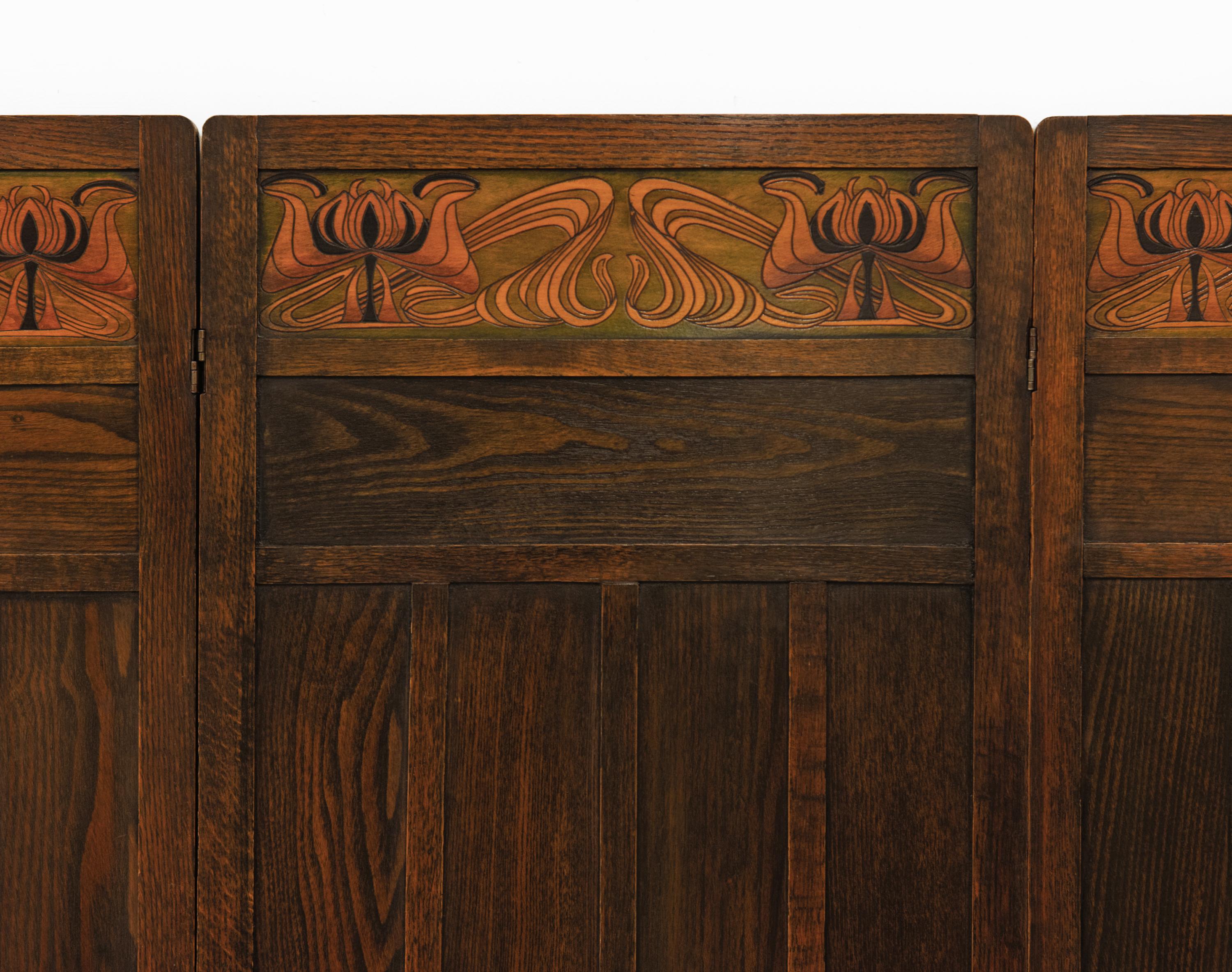 Arts & Crafts oak four fold room screen with sinuous stylised stained top panels. Attributed to Liberty & Co. Circa 1900.

Made in solid panelled oak with the Art Nouveau stained wood panels in beechwood.

In excellent condition, cleaned and waxed.