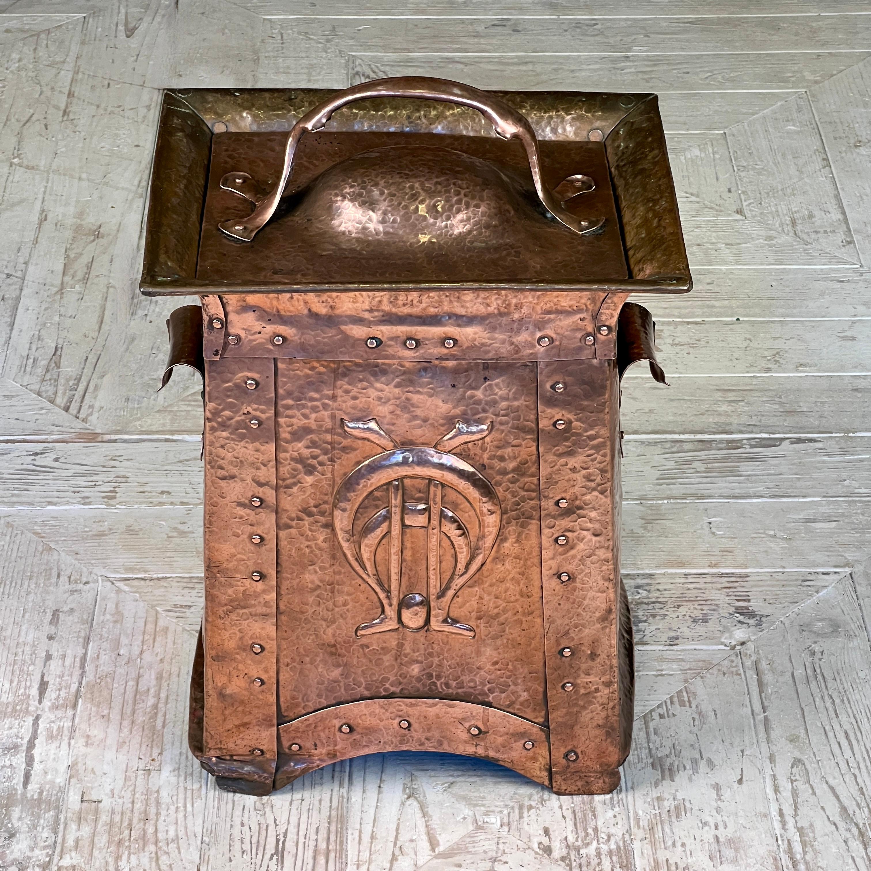 A rare Arts & Crafts copper coal, kindling, or log box by William Soutter & Sons of Birmingham (1760–1928). Circa 1890. Expertly crafted in hammered copper with a tapered form, it features striking decorative panels on both the front and back. The