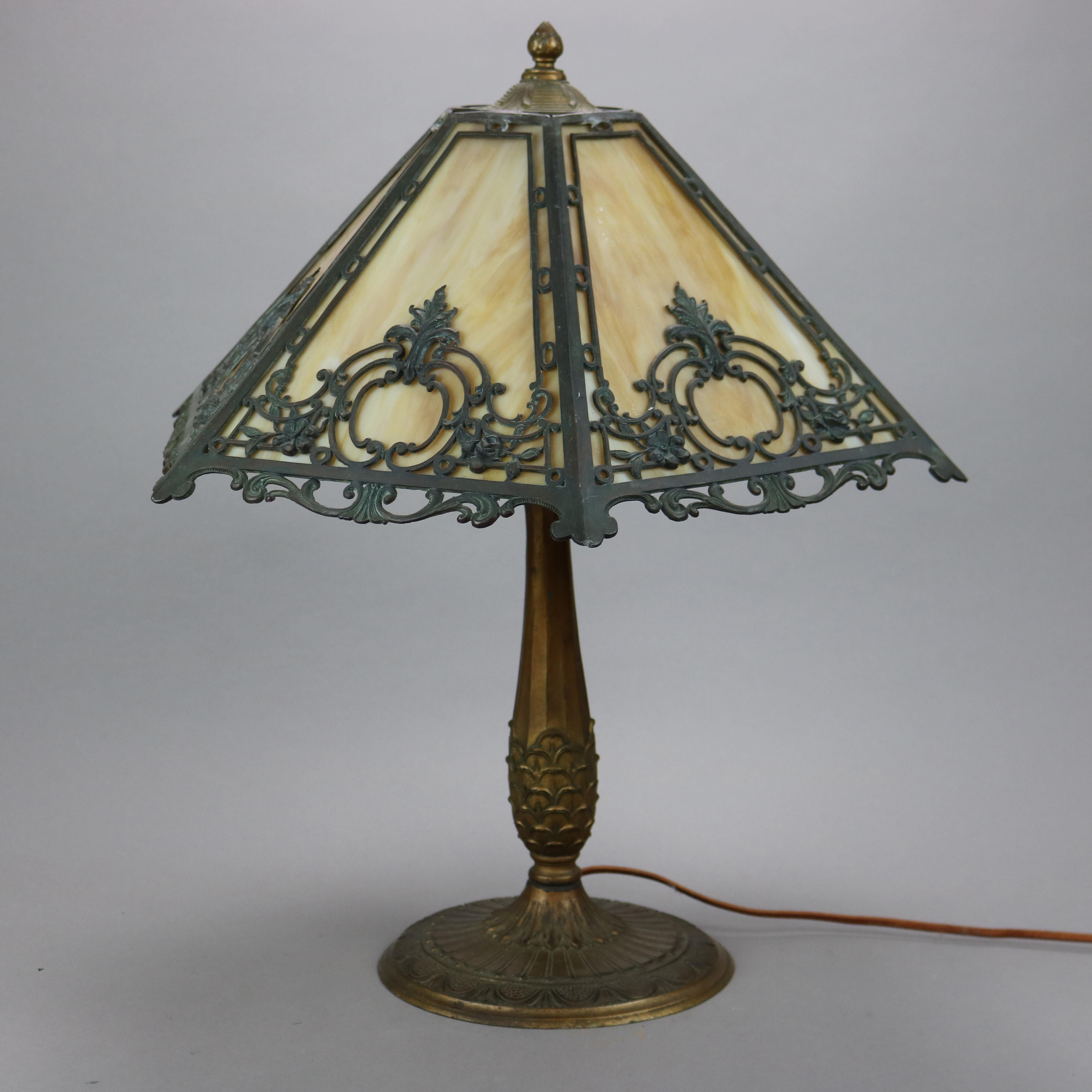 An antique Arts & Crafts table lamp by Bigelow and Kennard offers filigree cast shade having foliate, gadroon, and scroll design housing slag glass panels over double socket cast base with maker mark as photographed, c1920

Measures - 22.25''H X