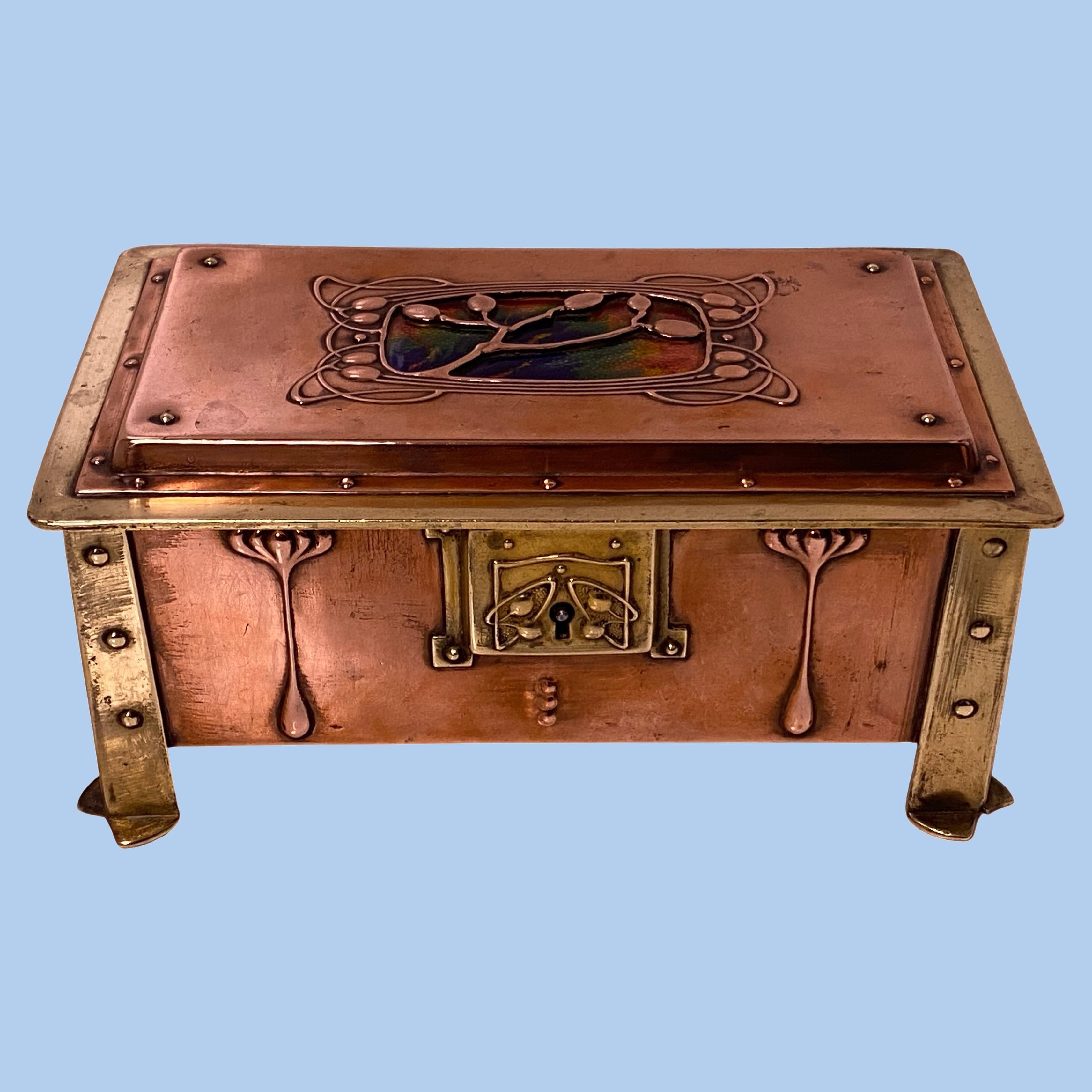 Arts & Crafts enamel, copper and brass box, circa 1900. The box of four turned rivet bracket brass cornices, the paneled copper body with stylised arts and crafts decoration, the cover with blue, green, yellow and burnt orange design enamel