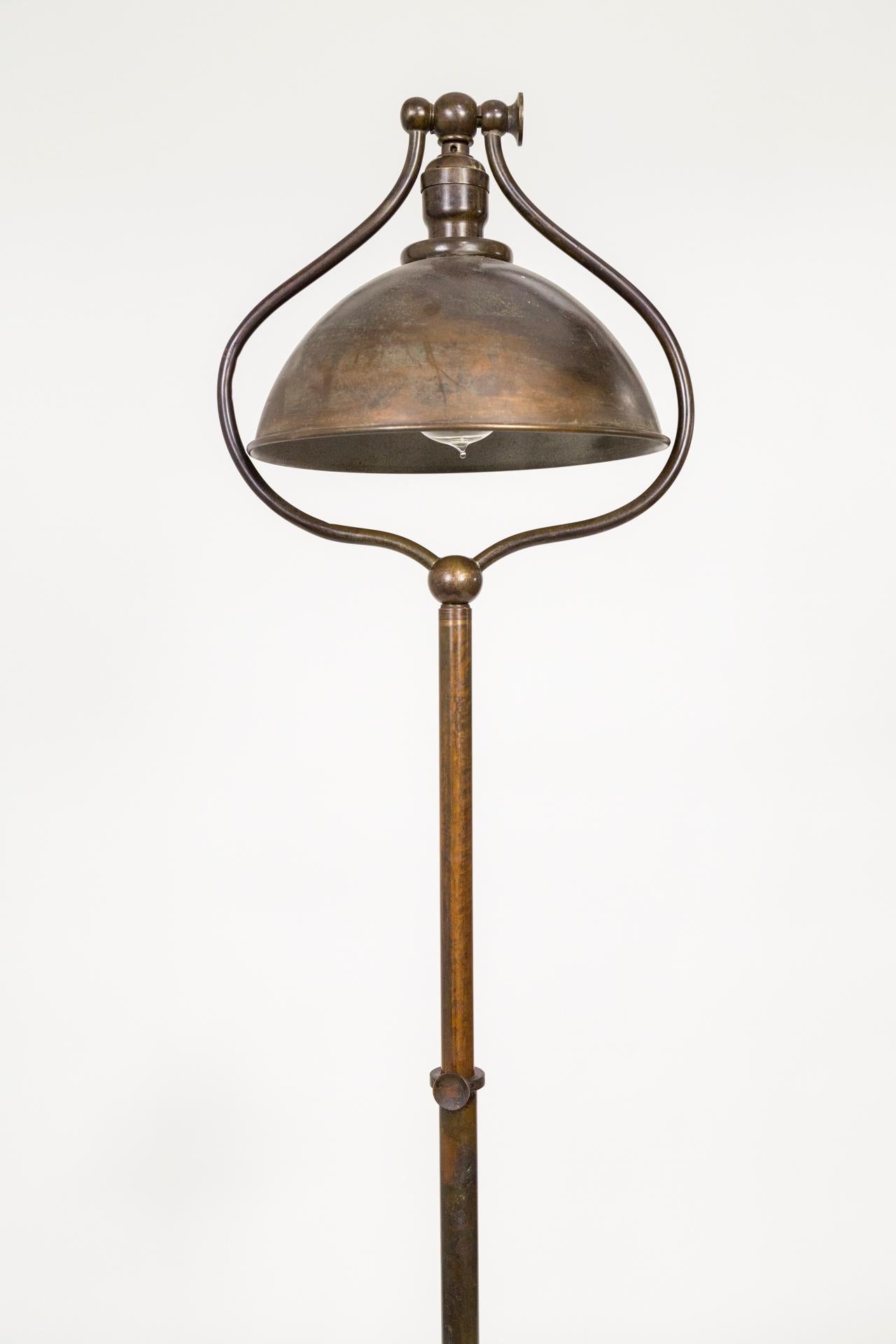A 1920s, all-metal, adjustable, smoker's floor lamp in by Bradley & Hubbard; with an articulating, dome shade - harp style - framed in a curved shape. Brass structure in a rich, brown patina, with a weighted base and match holder tray; newly