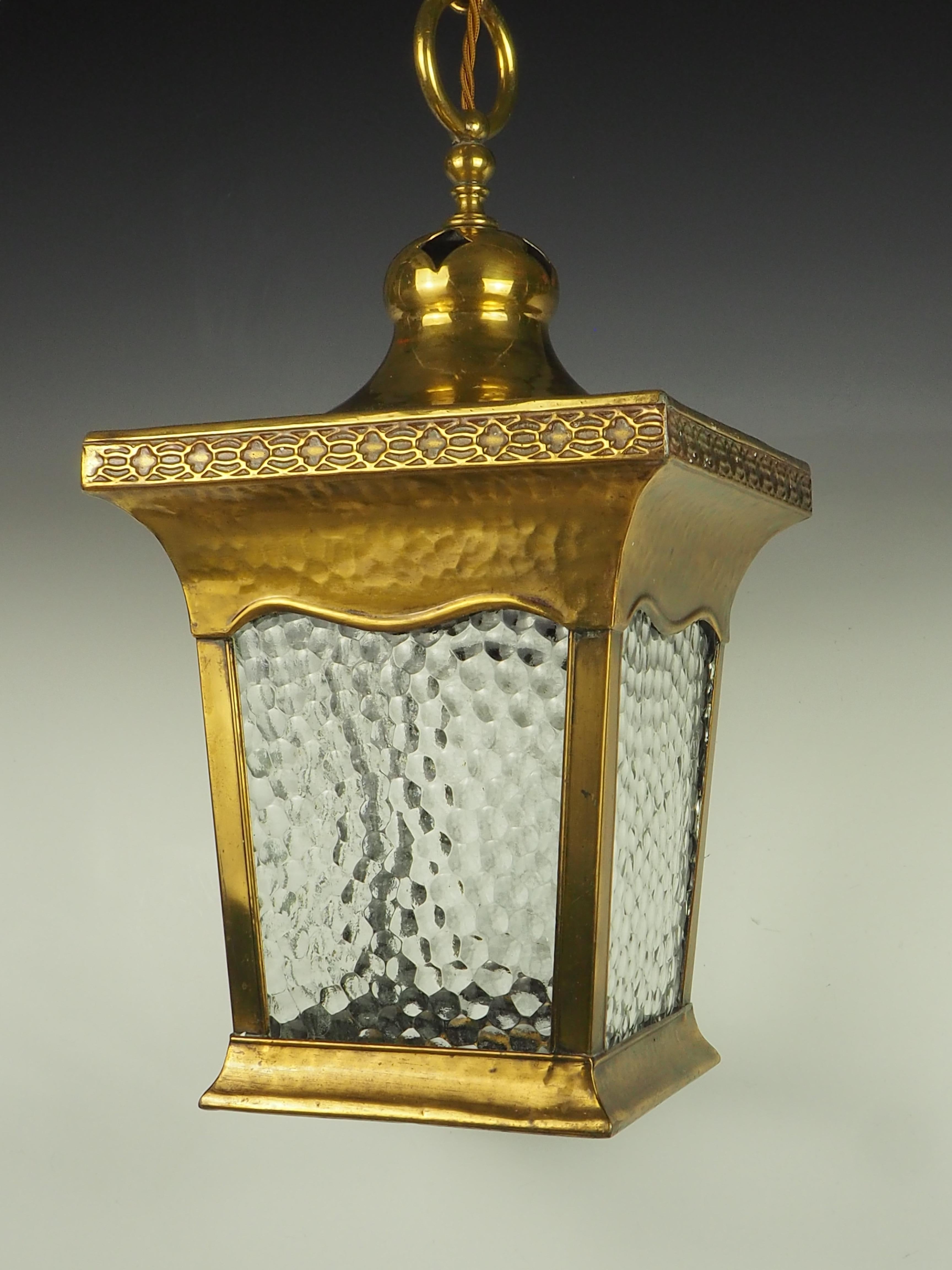 Arts & Crafts Brass Hall Lantern, eine vierseitige Leuchte, die Funktionalität und künstlerisches Design nahtlos miteinander verbindet.

Diese Laterne ist aus gehämmertem Messing gefertigt und weist eine einzigartige Struktur auf, die ihr Tiefe und