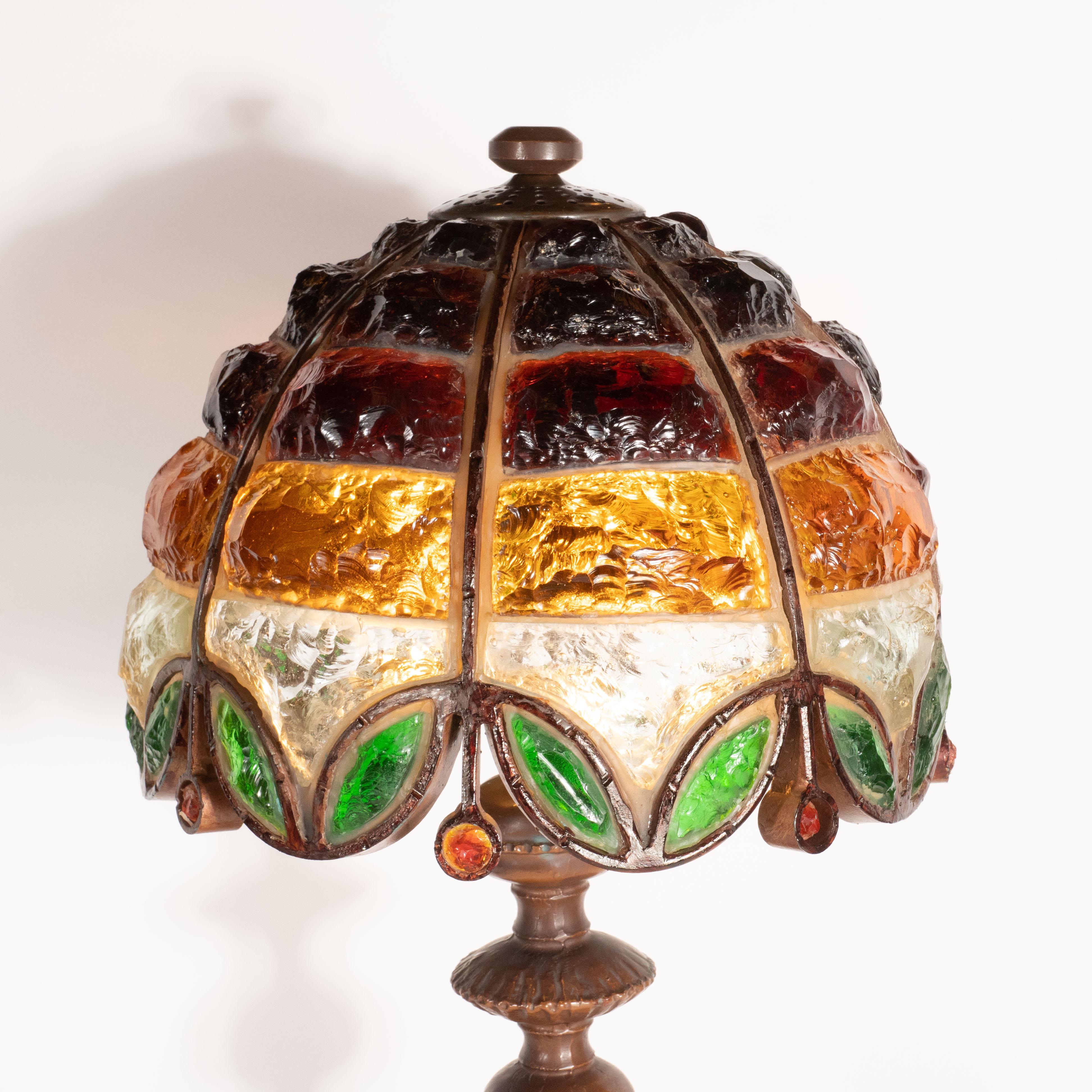 This gorgeous table lamp was crafted in the United States, circa 1920. It features a hand worked circular bronze base with a sculptural body offering an orbital detail in the center framed on either side by circular shell-like forms. The handblown