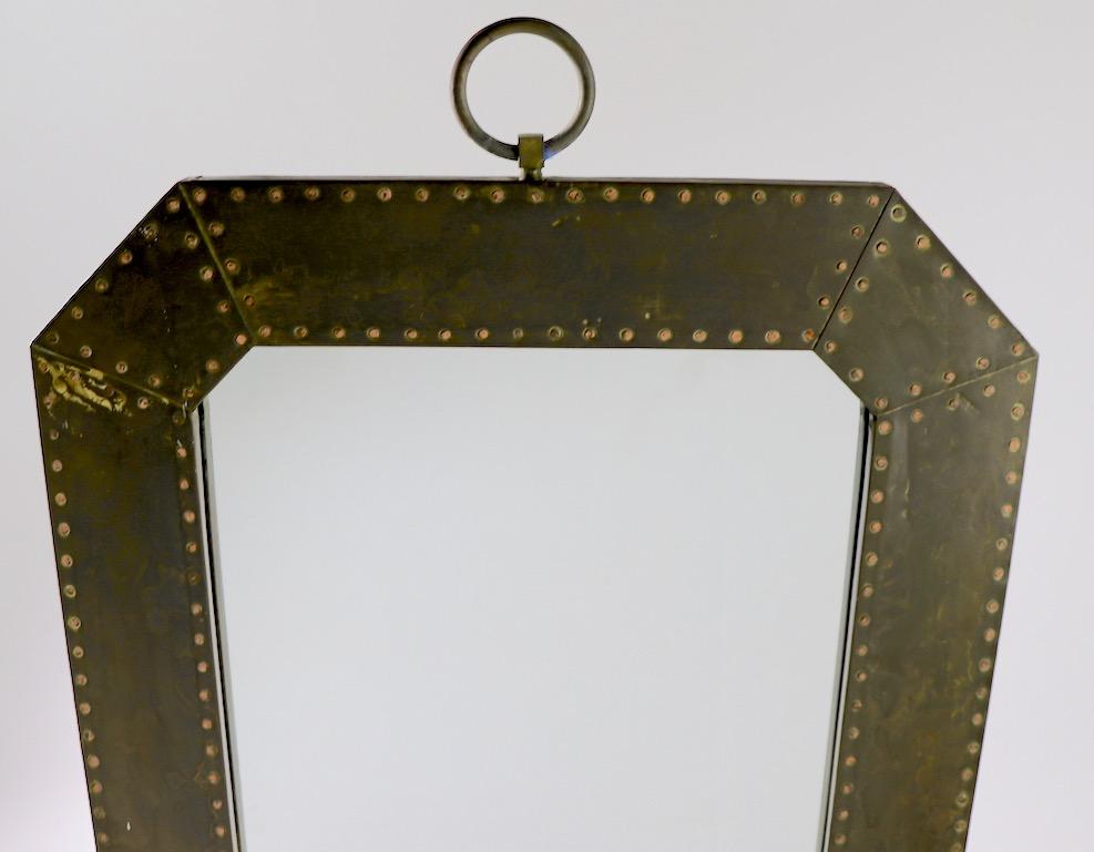 Eight sided studded copper frame surrounds the plate glass mirror. Clean, original, ready to hang condition. Metal surface shows light cosmetic wear, normal and consistent with age. Frame 4.25 inches wide.