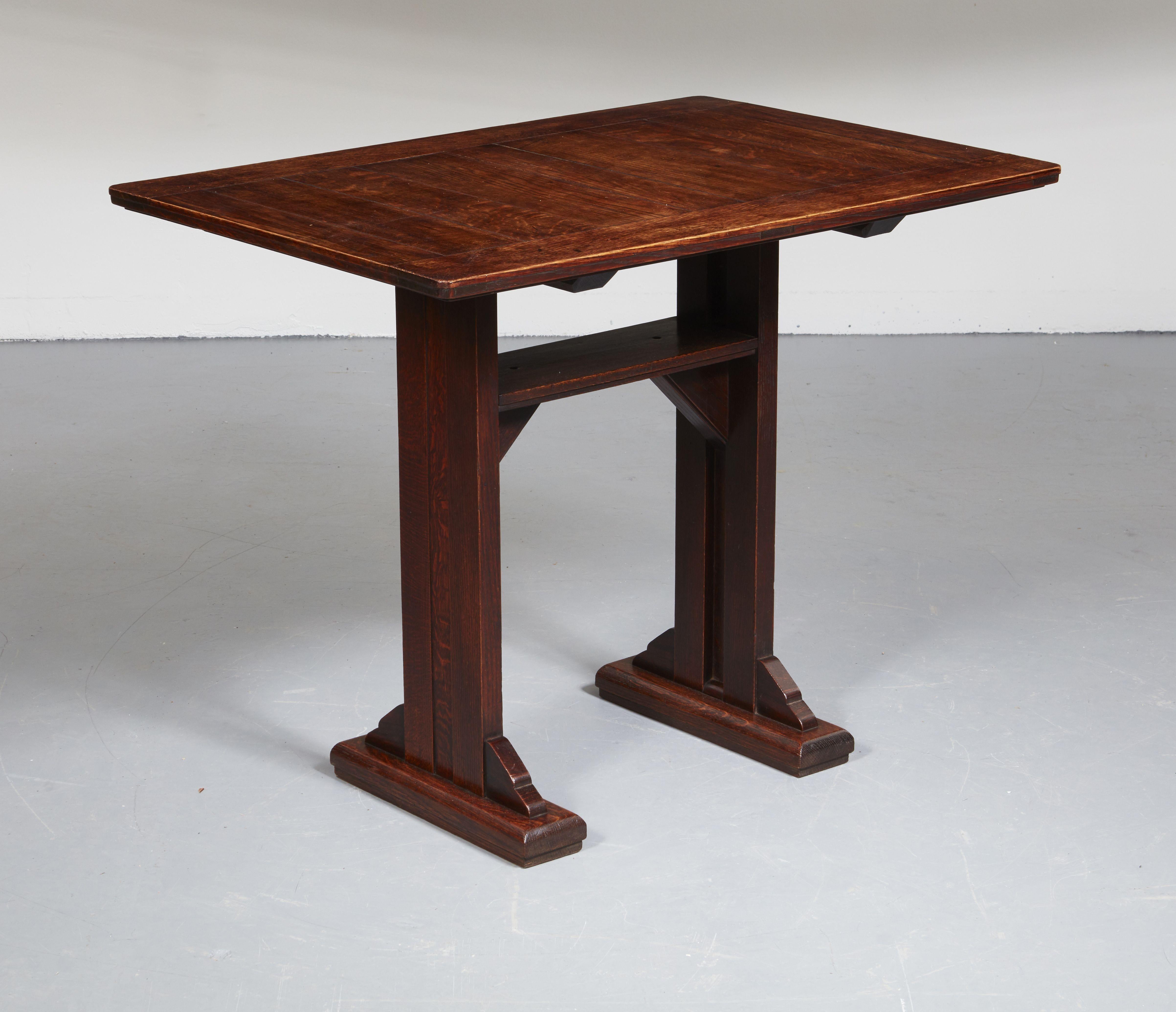 An English Arts & Crafts center table in oak with rectangular top of substantial panel construction over boarded straight legs with central reveal on shoe feet with solid shaped diagonal braces and high-level stretcher with triangular braces. Solid