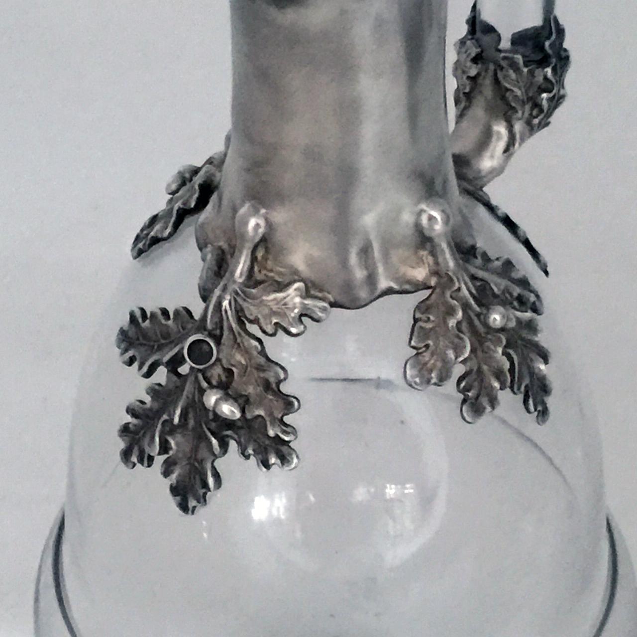 Part of the Arts & Crafts design movement these claret jugs are exceptional and unique. The hand blown crystal bases are in the form of acorns. The column and tops are of burnished silver in the shape of gnarled oak branches with applied decoration