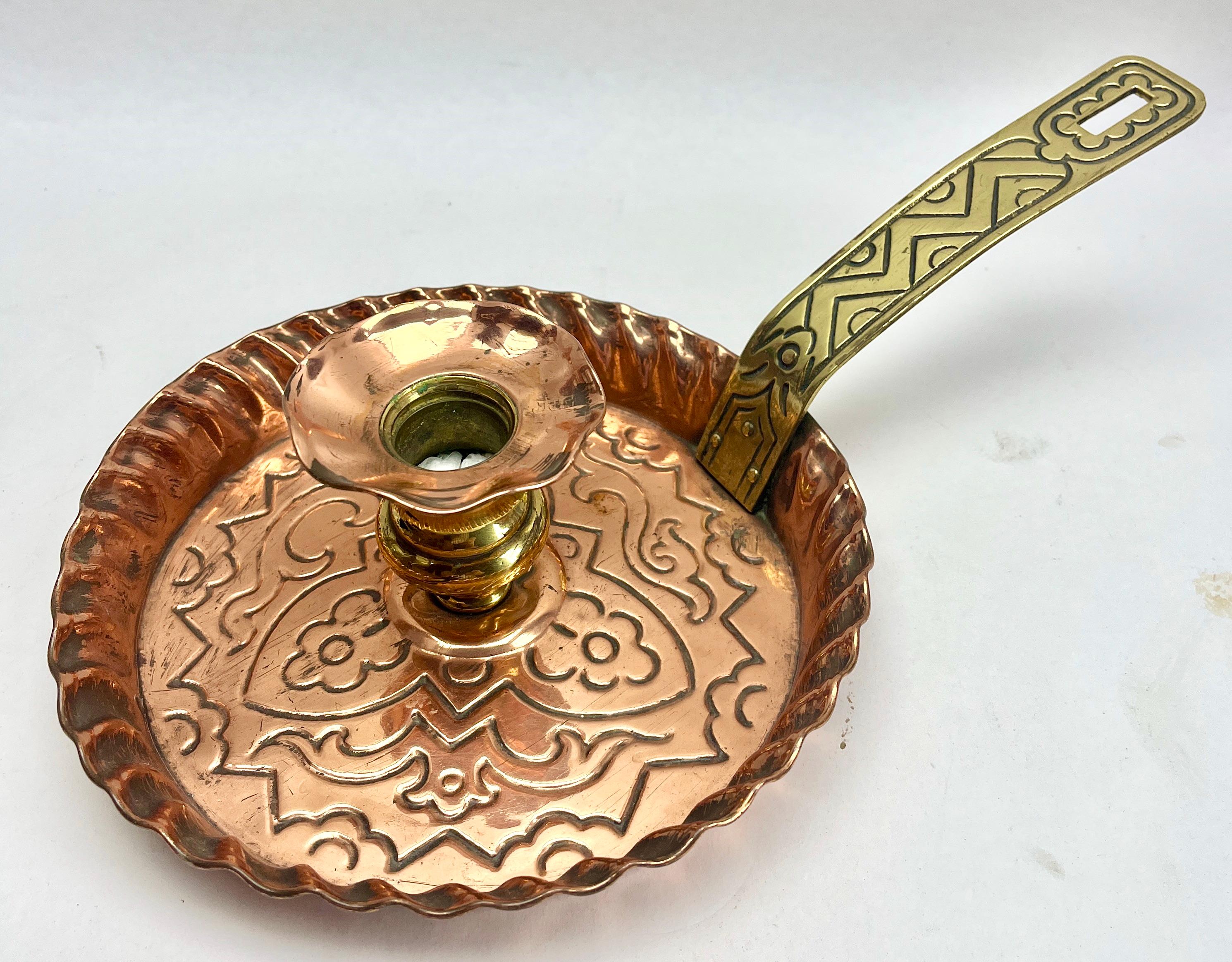 Arts and Crafts copper and brass candlestick Germany. 
The base, handle and drip tray are constructed of copper and the upright candle holder is in brass. with a distintive concave curved handle that slots into the drip tray. 

The piece is in Good