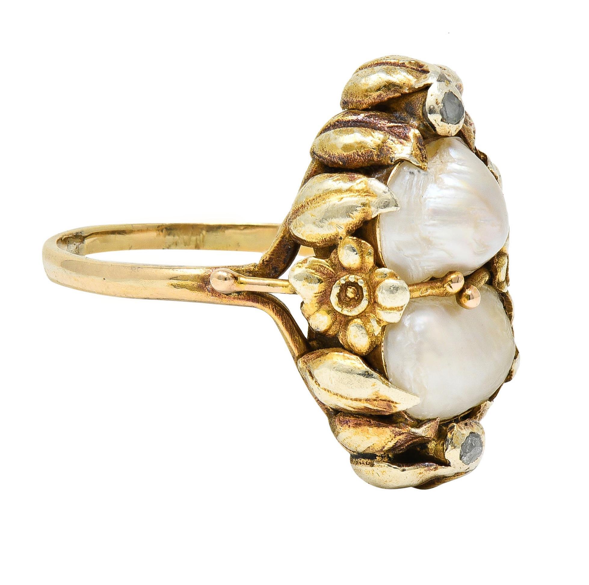 Centering two baroque pearls organically shaped and ranging in size from 5.5 to 7.5 mm 
White in body color with strong iridescence - set with stylized foliate motif prongs
Flanked north to south by approximately 0.05 carat of rose cut diamonds 
Eye