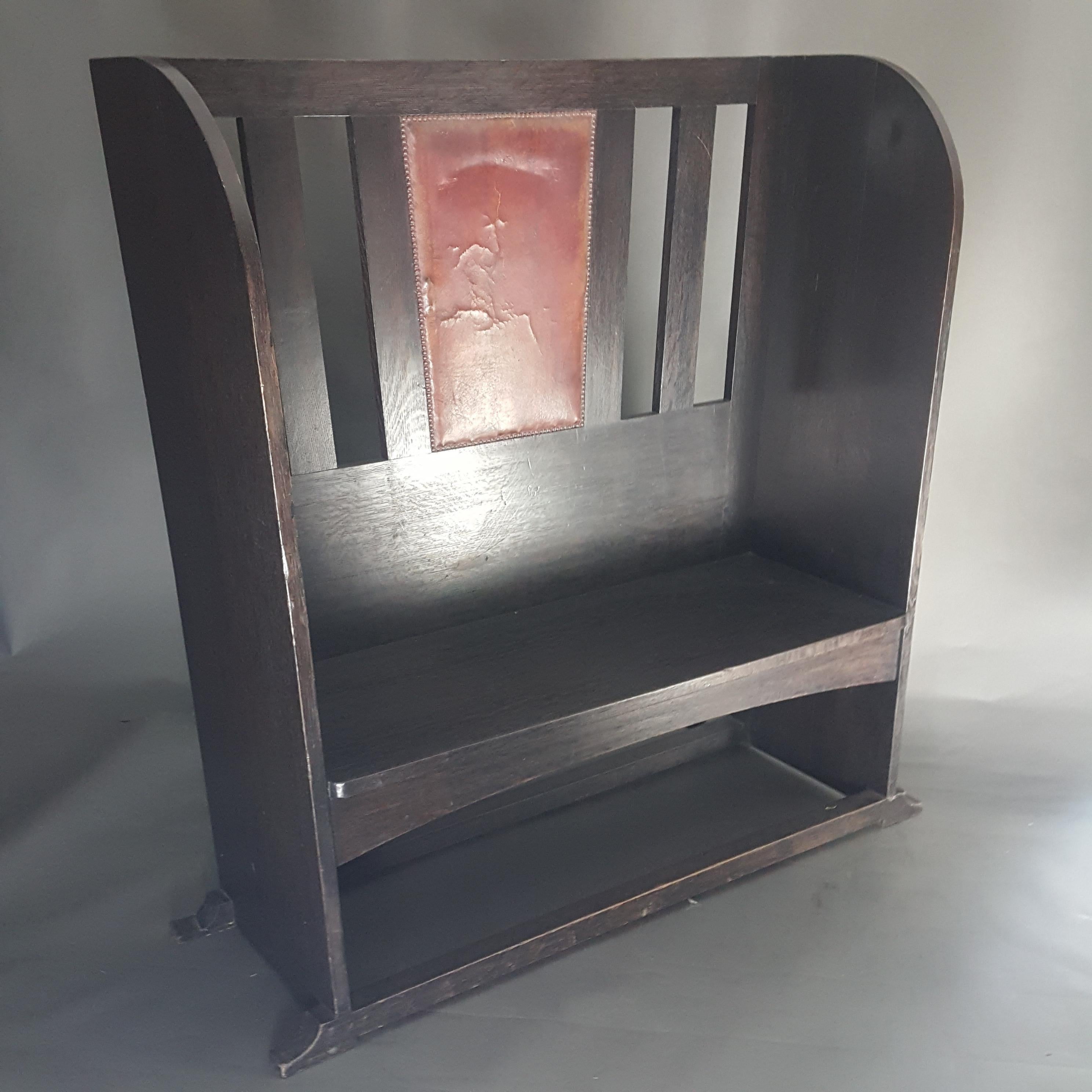 Original Arts & Crafts Movement ebonised oak settle or hall seat dating to around 1900. The settle has it's original ebonised finish and leather upholstered panel to which there is some cracking. We have given the width as 45