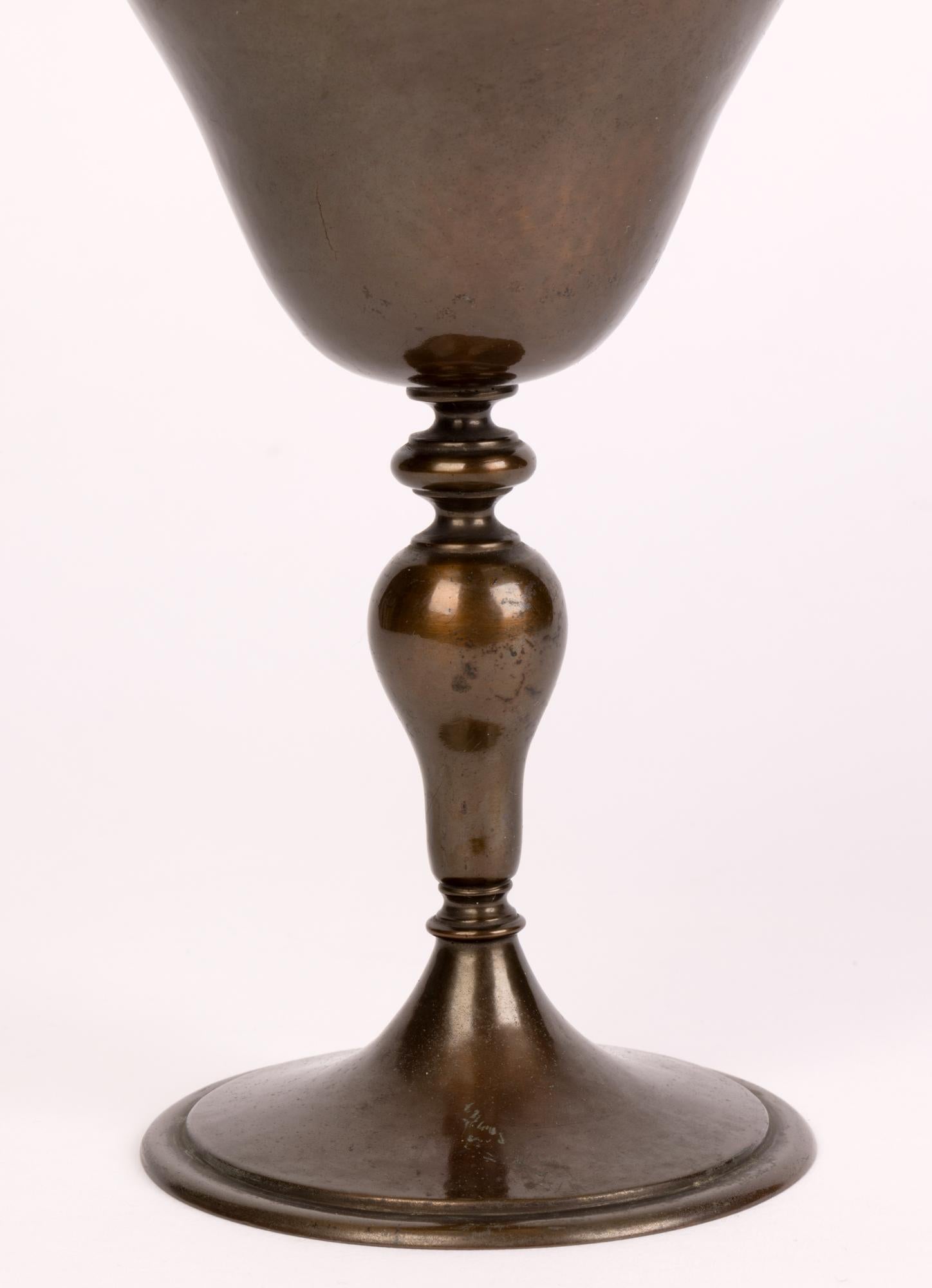 A very stylish Arts & Crafts with Gothic elements Edwardian hand crafted patinated copper lidded communion chalice dating from the early 20th Century. The chalice stands raised on a rounded pedestal foot with a ball knop stem and with a shaped body