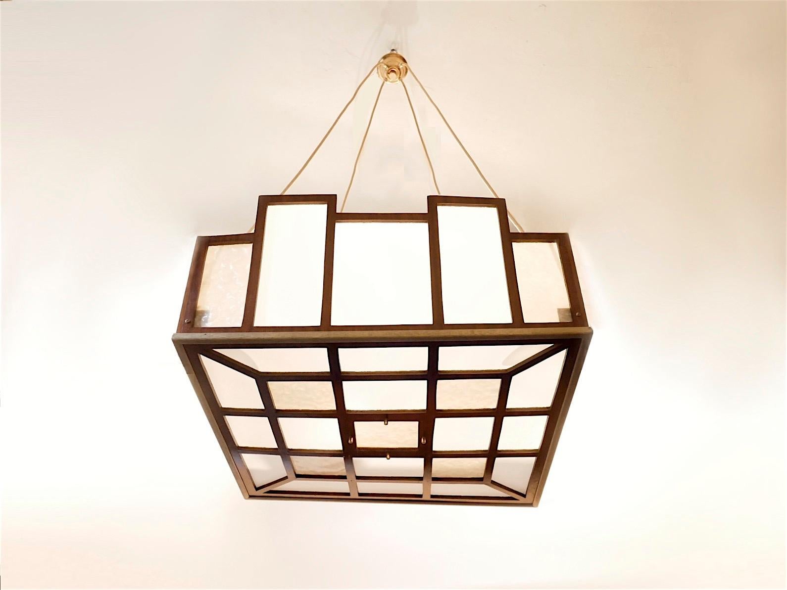 Extra large sized early 20th century pendant lamp, Arts & Crafts design with a very light weight wooden geometrical structure in mahogany wood veneer matched with brass components, bi-colored acrylic diffuser.