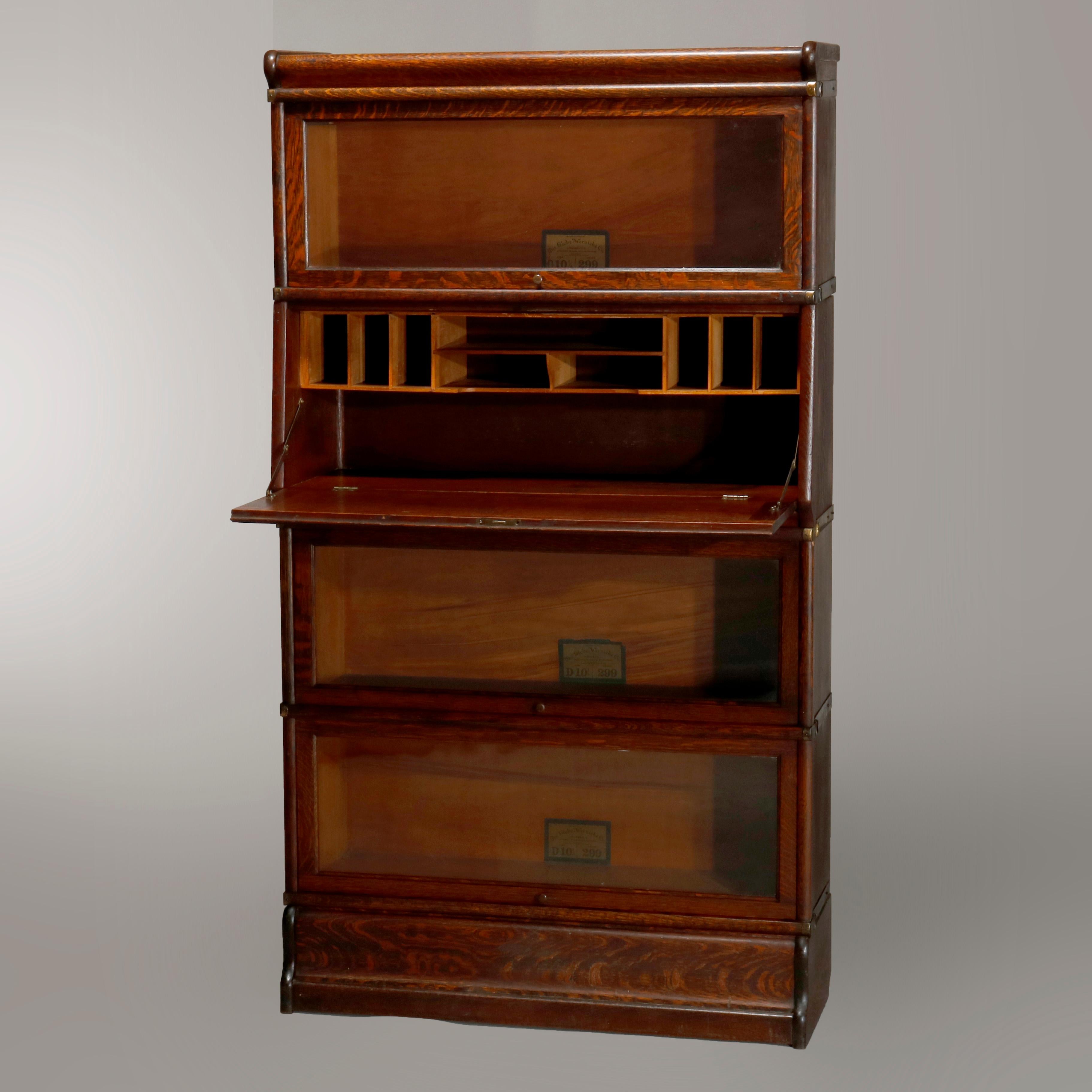 An antique Arts & Crafts Mission Barrister stacking bookcase by Globe Wernicke offers oak construction with four sections having pull-out glass doors and drop desk interior, original labels as photographed, circa 1910.

Measures: 61.5