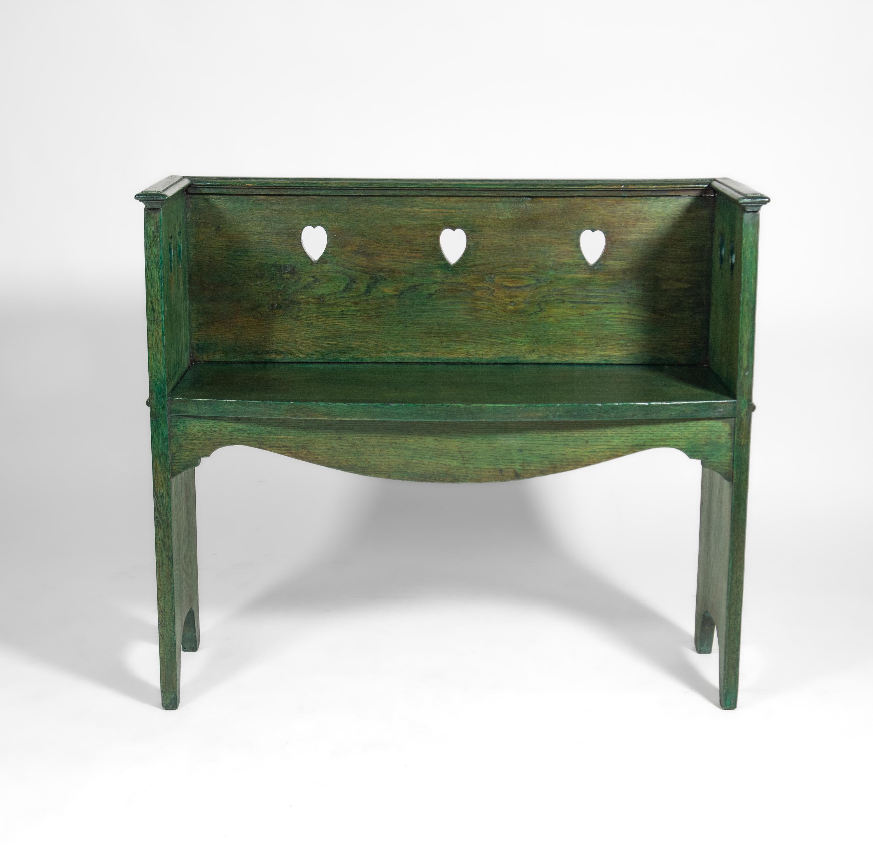 An wonderful arts and crafts movement green stained oak small bench seat, with heart shaped cut out decoration. Circa 1900.

The solid oak bench in a Charles Voysey manner has been stained green. It has an Aqua Coat sealer for durability, and a