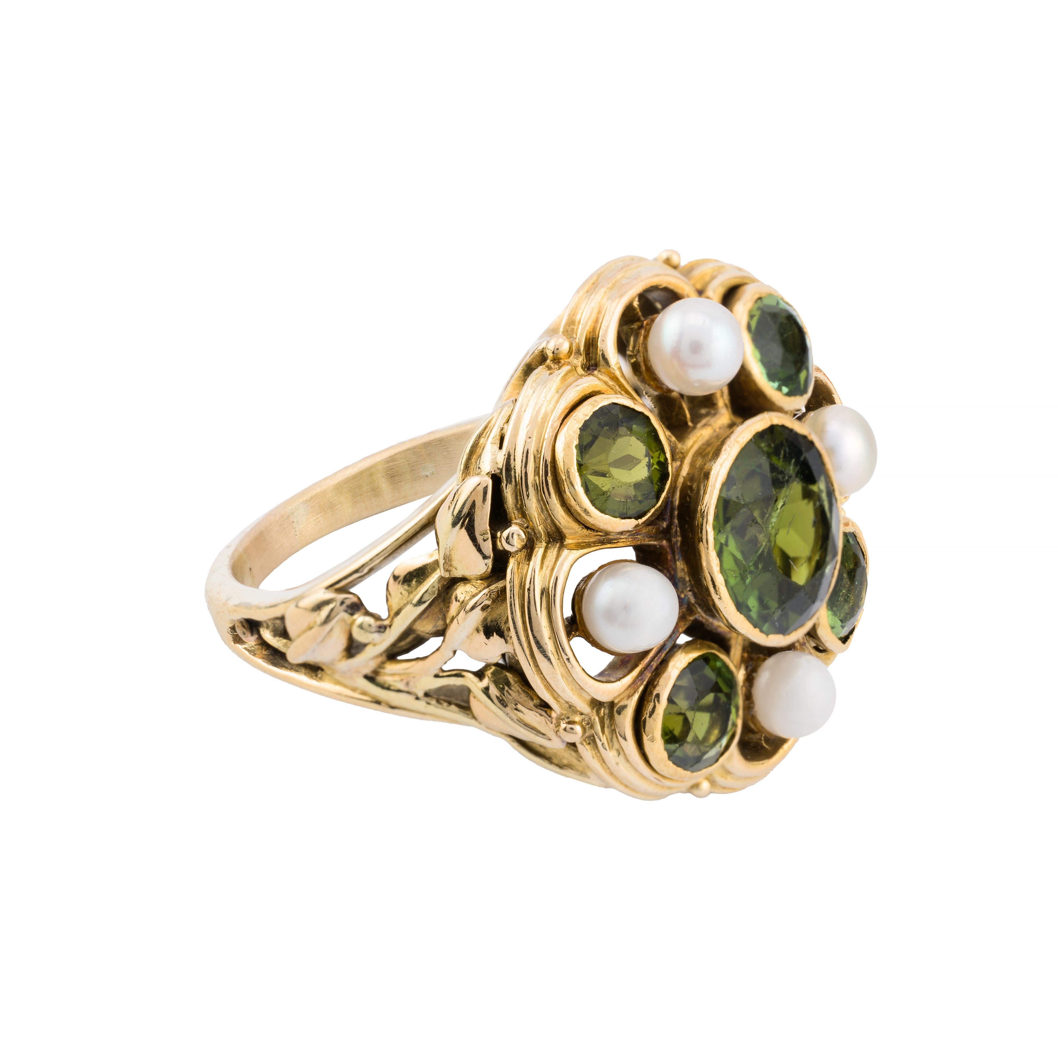 Aston Estate Jewelry Presents:

A striking Arts and Crafts ring in the manner of Edward Oakes featuring a 2.50 carat Old European-cut green tourmaline at its center. Surrounding the central stone are additional Old European-cut green tourmalines