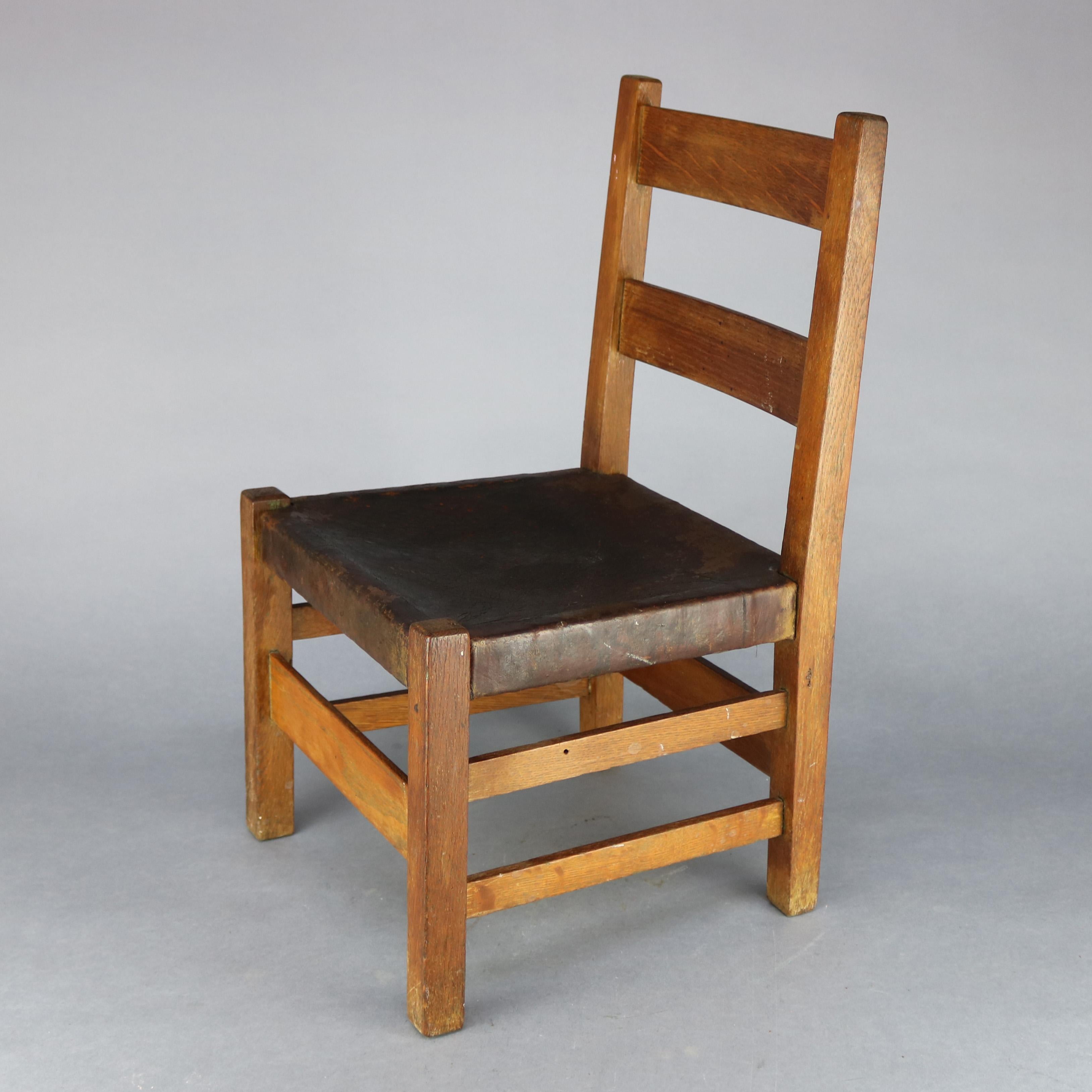 An antique Arts and Crafts Mission Child's Small Chair by Gustav Stickley, Catalog #344, offers oak construction with slat back over leather seat and raised on square and straight legs, signature mark not visible but chair is represented in Gustav