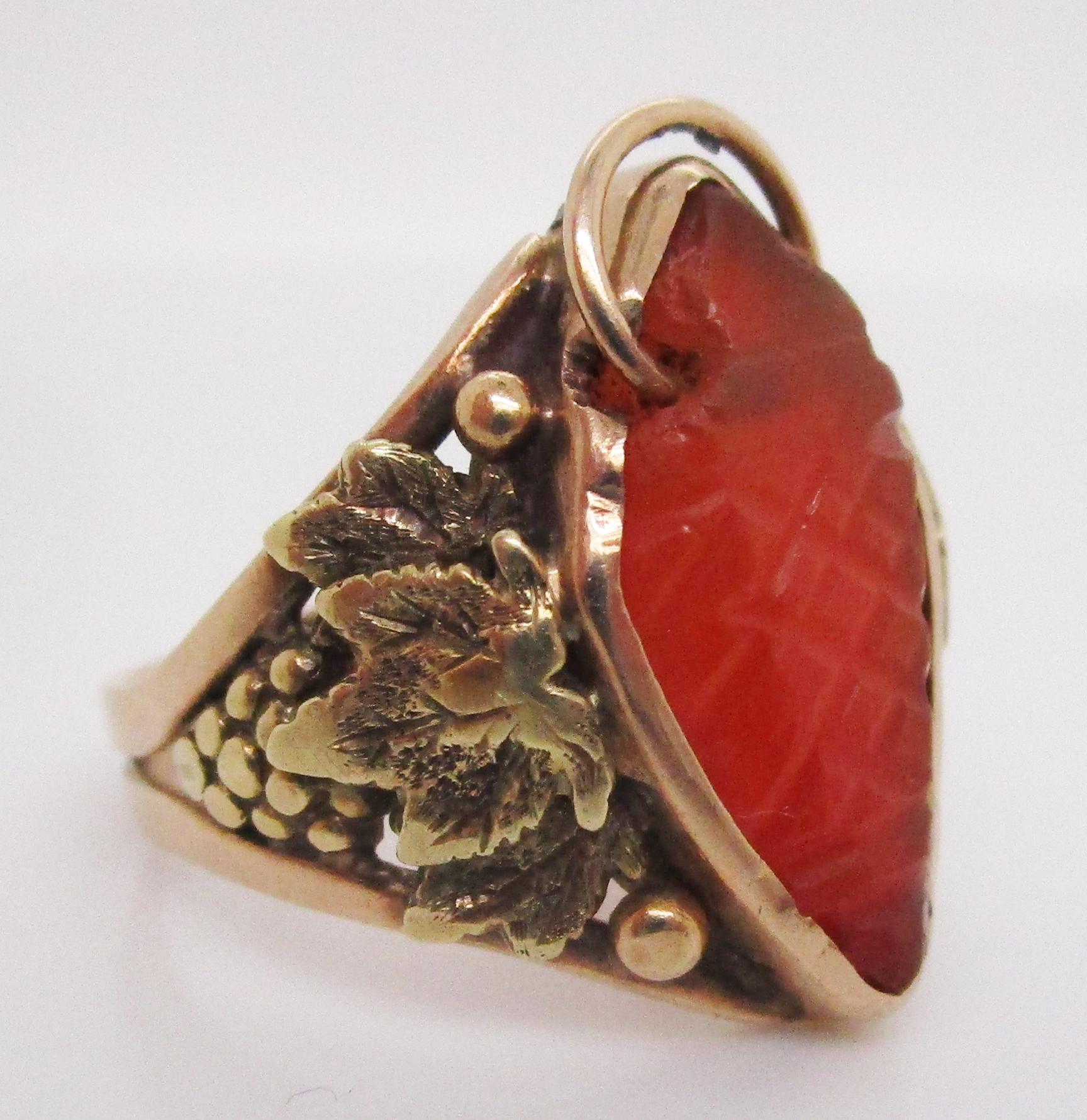 This gorgeous ring exemplifies the best of the Arts and Crafts movement in its spectacular combination of 14k yellow gold, repurposed carved carnelian, and hand-crafted grape and leaf motifs set ever so delicately on the shoulders! The center stone