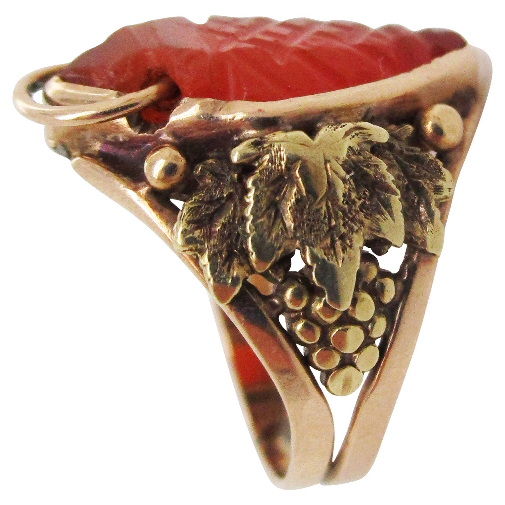 This gorgeous ring exemplifies the best of the Arts and Crafts movement in its spectacular combination of 14k yellow gold, repurposed carved carnelian, and hand-crafted grape and leaf motifs set ever so delicately on the shoulders! The center stone