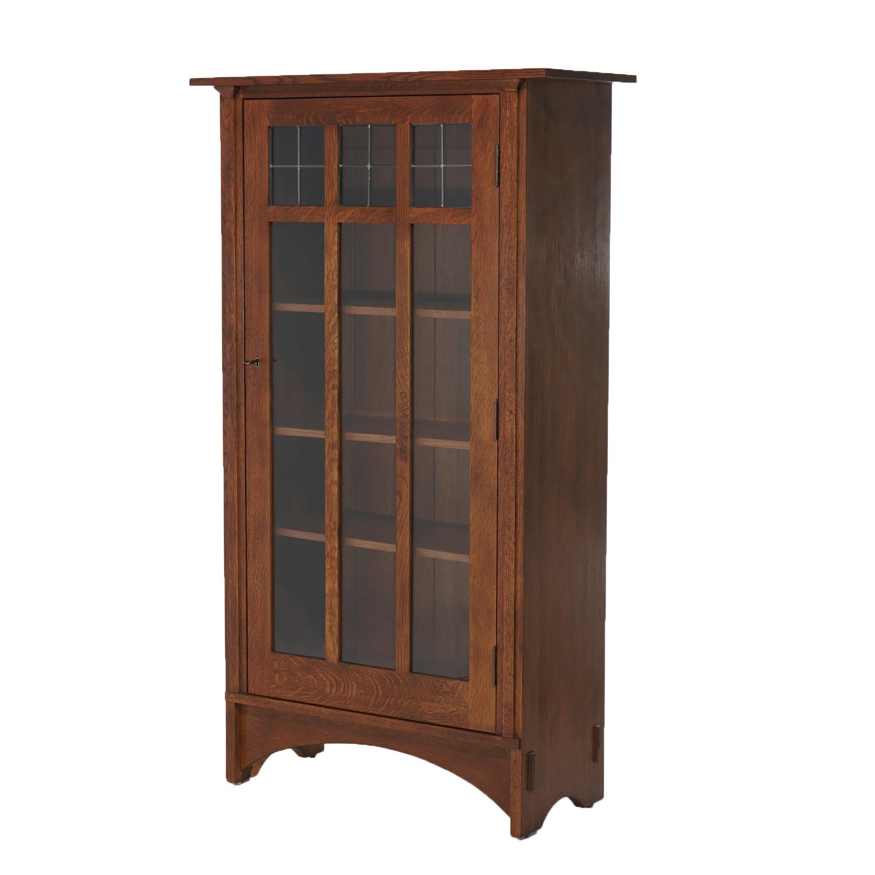 An Arts and Crafts Harvey Ellis design bookcase by Stickley offers quarter sawn oak construction with single door having paneled glass and leaded glass construction opening to adjustable shelf interior, maker stamps en verso as photographed, 20th