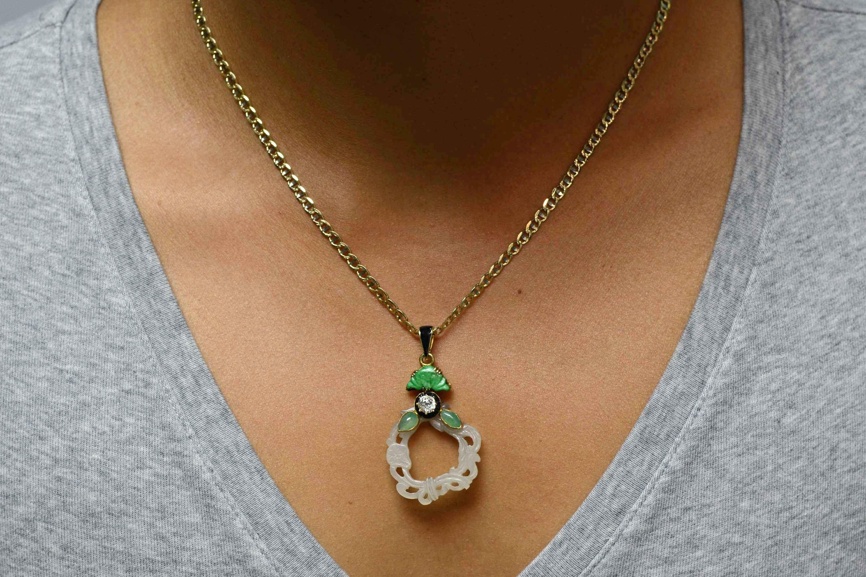 An authentic antique Arts & Crafts jade pendant with many elements that combine in a synergistic flow. The sinuous carving of the water jade is flanked by apple green pears, topped with an old mine cut 1/3 carat diamond surround by French cut black