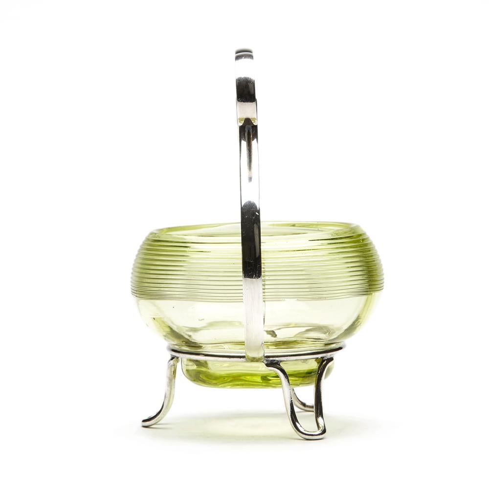 Un elegante piatto da bon bon in argento placcato in stile Arts & Crafts di James Dixon con rivestimento rimovibile in vetro verde con motivo a filo attribuito a Stevens & Williams. Il supporto argentato si erge su tre piedini aperti in filo