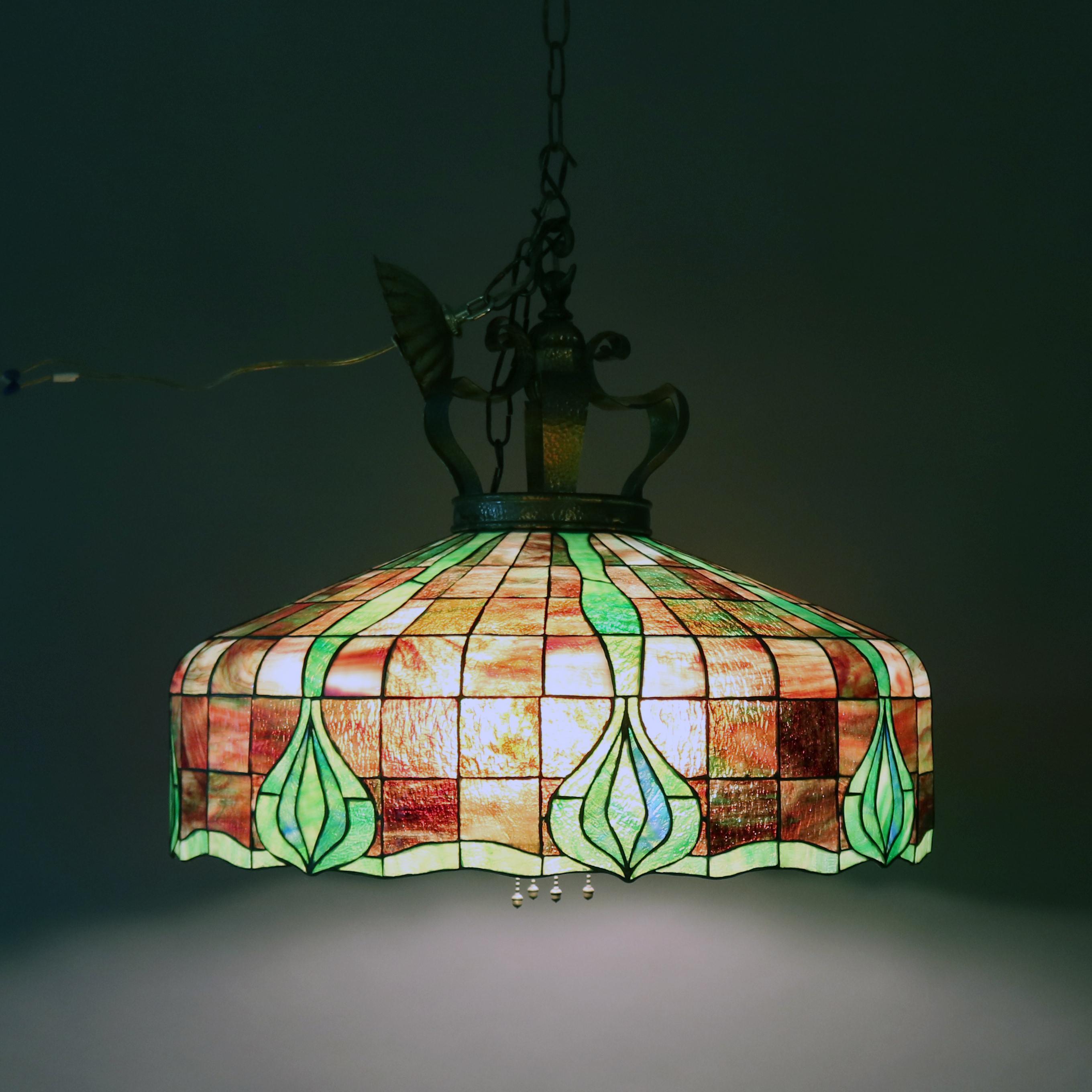 An antique Arts & Crafts leaded stained and slag glass mosaic chandelier features dome form with four independently controlled pull chain lights, circa 1910.

Measures - 22