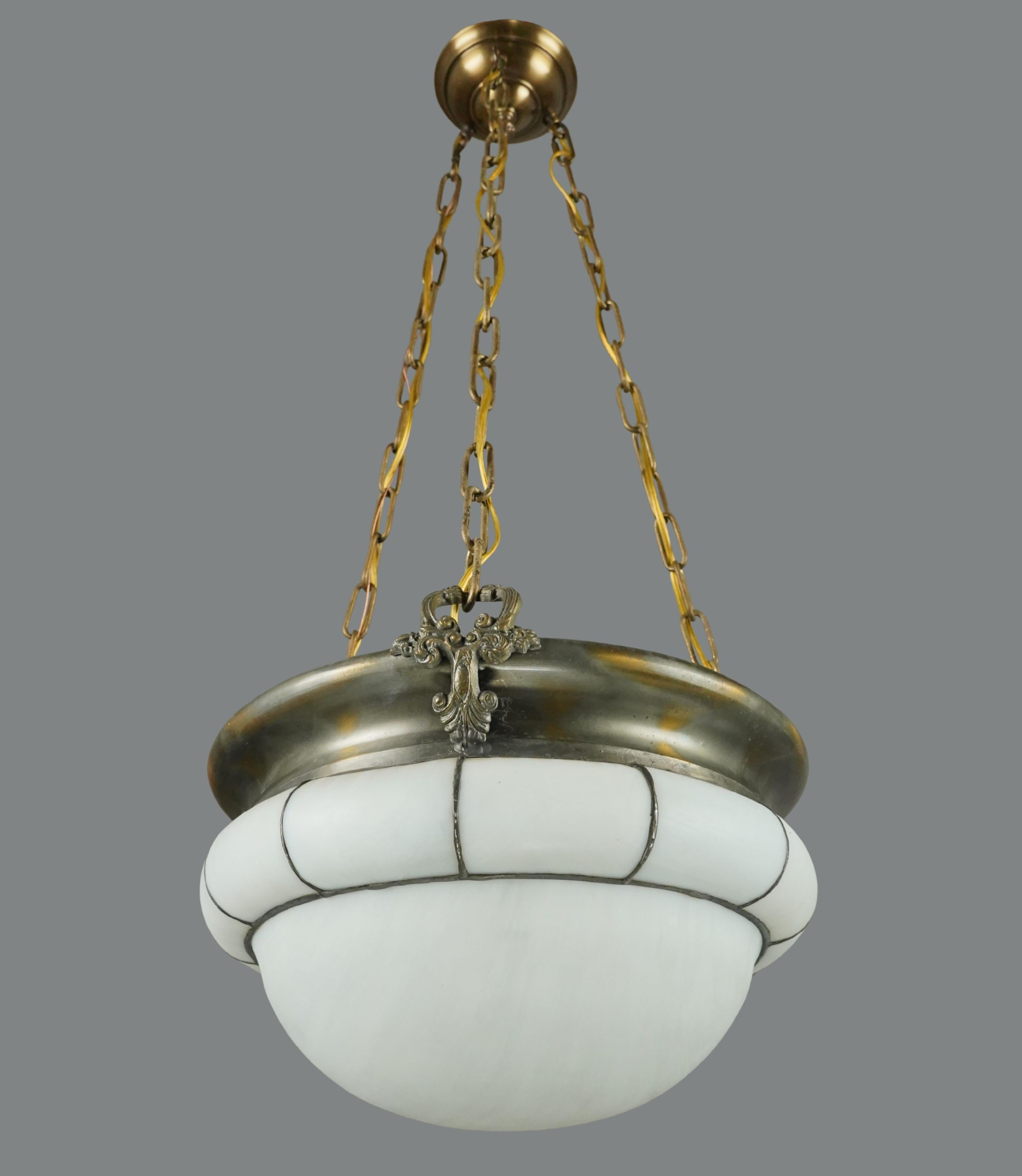 Arts & Crafts style pendant light featuring a white molded and leaded glass bowl, an antique brass rim, and a steel chain. This requires three standard Edison style medium base bulbs. Cleaned and restored. Good condition with surface wear from prior