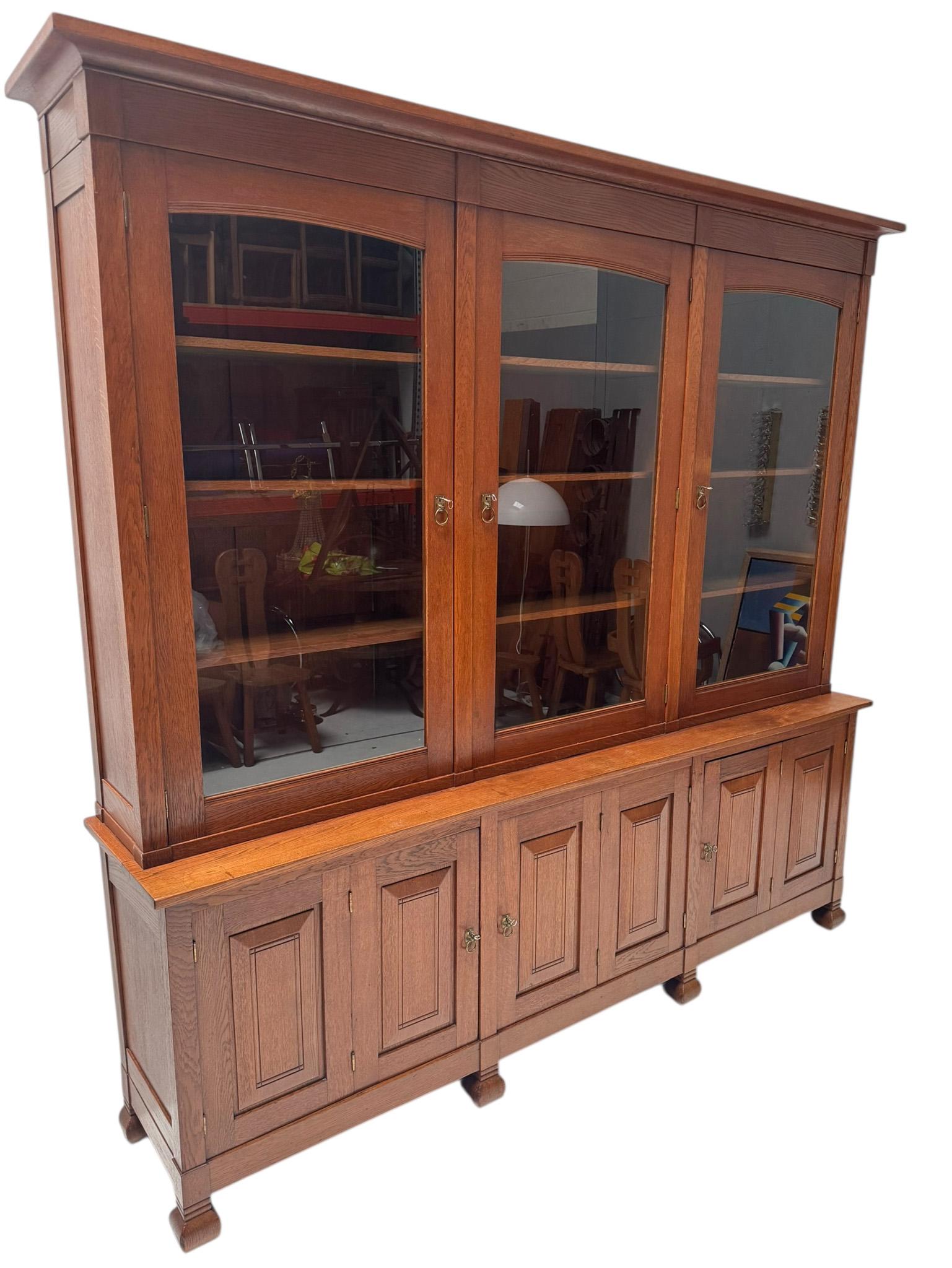 Magnifique et rarissime bibliothèque Arts & Crafts.
Design/One par Willem Penaat pour De Woning Amsterdam.
Un design néerlandais saisissant des années 1900.
Chêne massif avec verre d'origine et six poignées d'origine en laiton patiné conçues par Jan