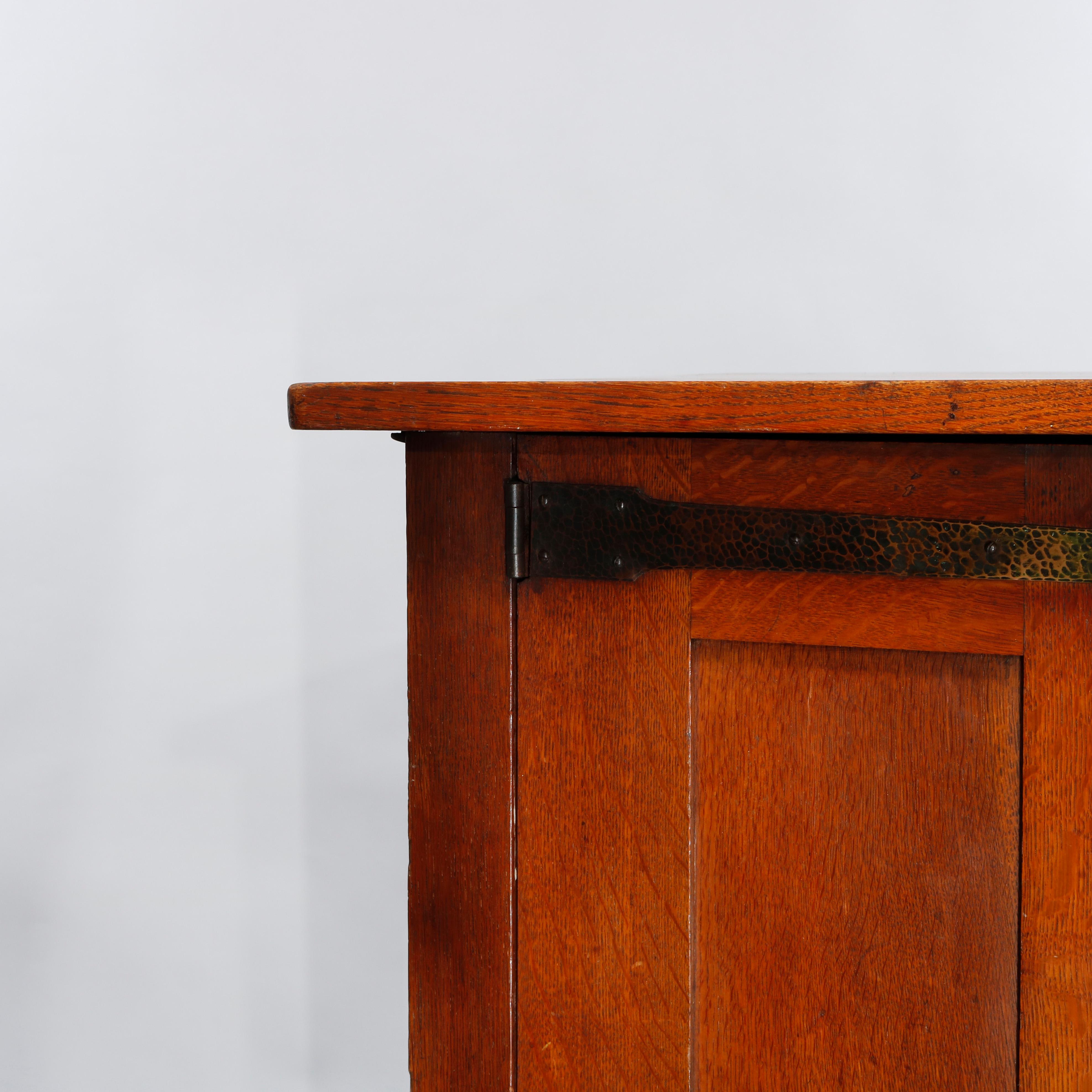An antique Arts & Crafts Mission sideboard by L&JG Stickley offers paneled quarter sawn oak construction with central drawer tower having flanking cabinets and over lower long drawer, raised on straight and square legs, hammered copper strap hinges