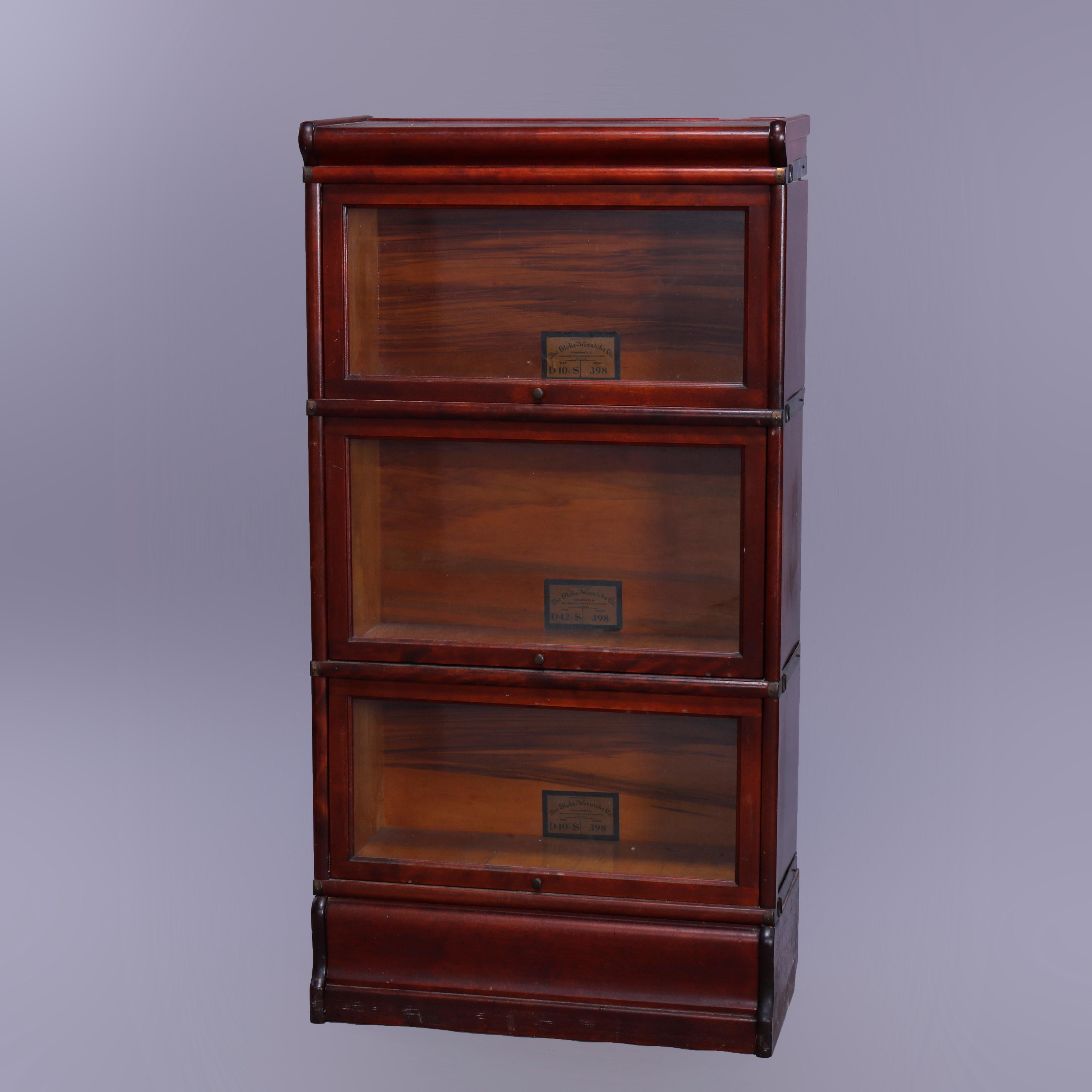 An antique Arts & Crafts Barrister bookcase by Globe Wernicke offers mahogany construction in diminutive form having three stacks, each with pull-out glass doors, seated on ogee base, original labels as photographed, c1910

Measures - 49.5'' H x
