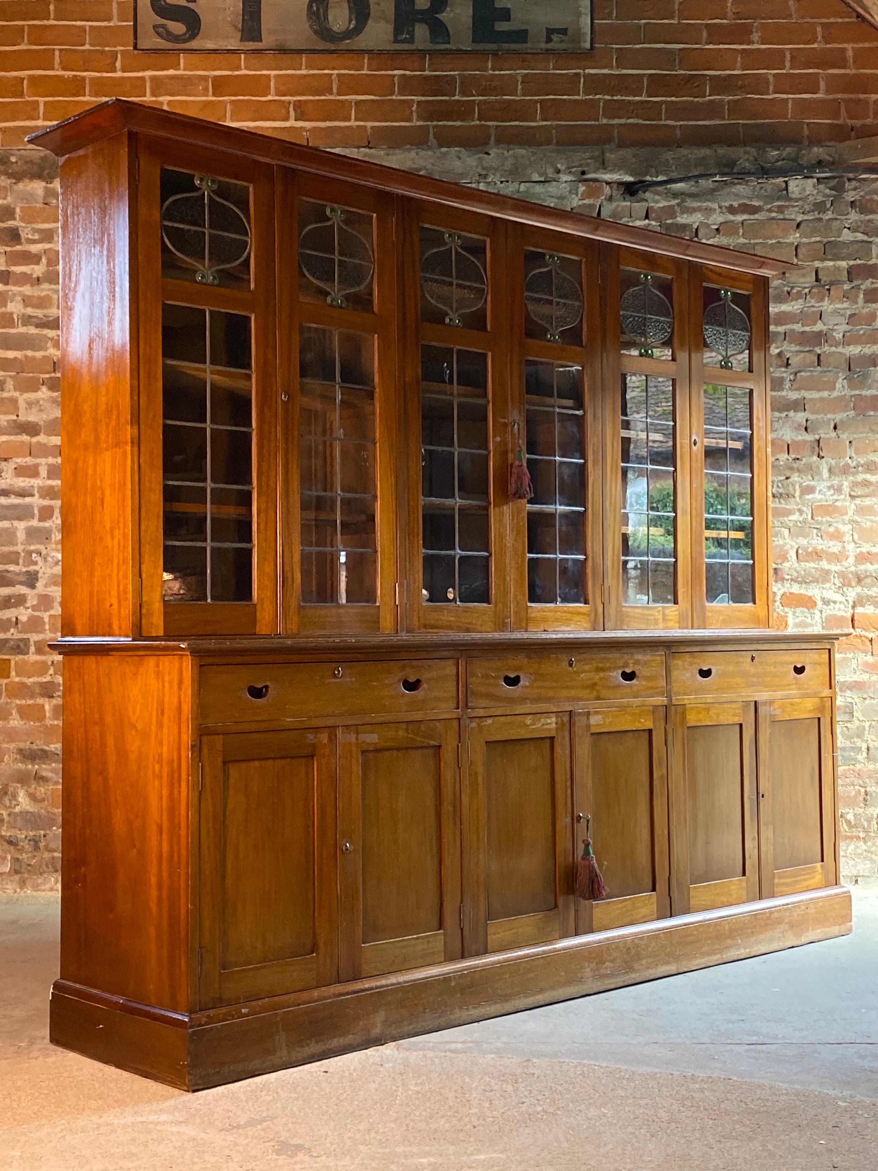 Arts & Crafts mahogany library bookcase extremely large, circa 1920

Magnificent large and imposing Arts & Crafts mahogany library bookcase circa 1920s, The corniced upper section over 6 leaded light glazed cupboard doors each with stained floral