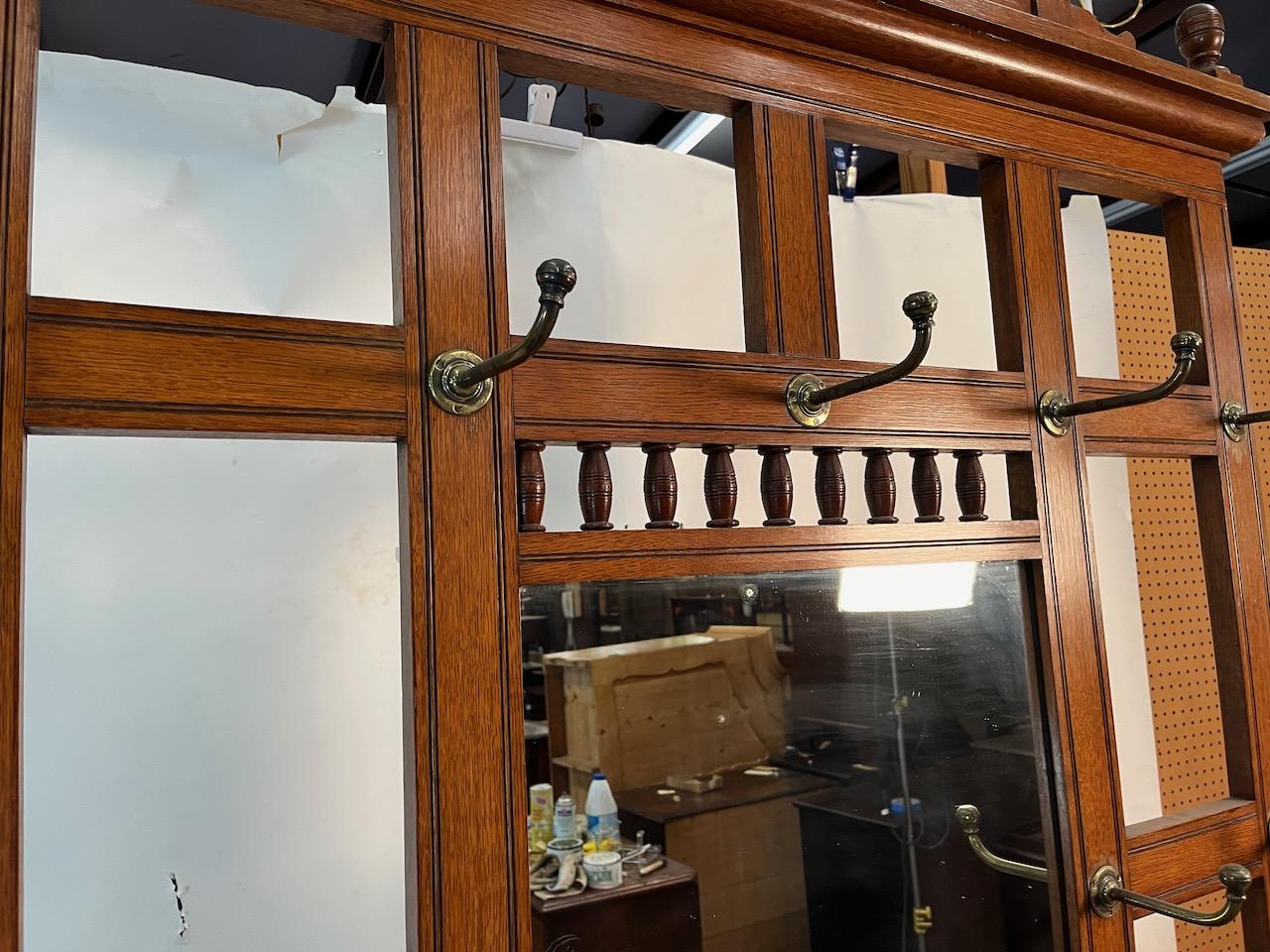 Outstanding example of an Arts & Crafts hall mirrored hall tree with nine original crafted brass hooks and three tile decorated center panel. Glove drawer is intact with two metal water receptacles in the base.