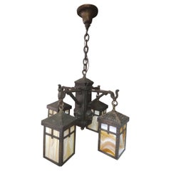 Mission Arts & Crafts Lampadario in ottone con paralumi in vetro scoria e teste di monaco C1910