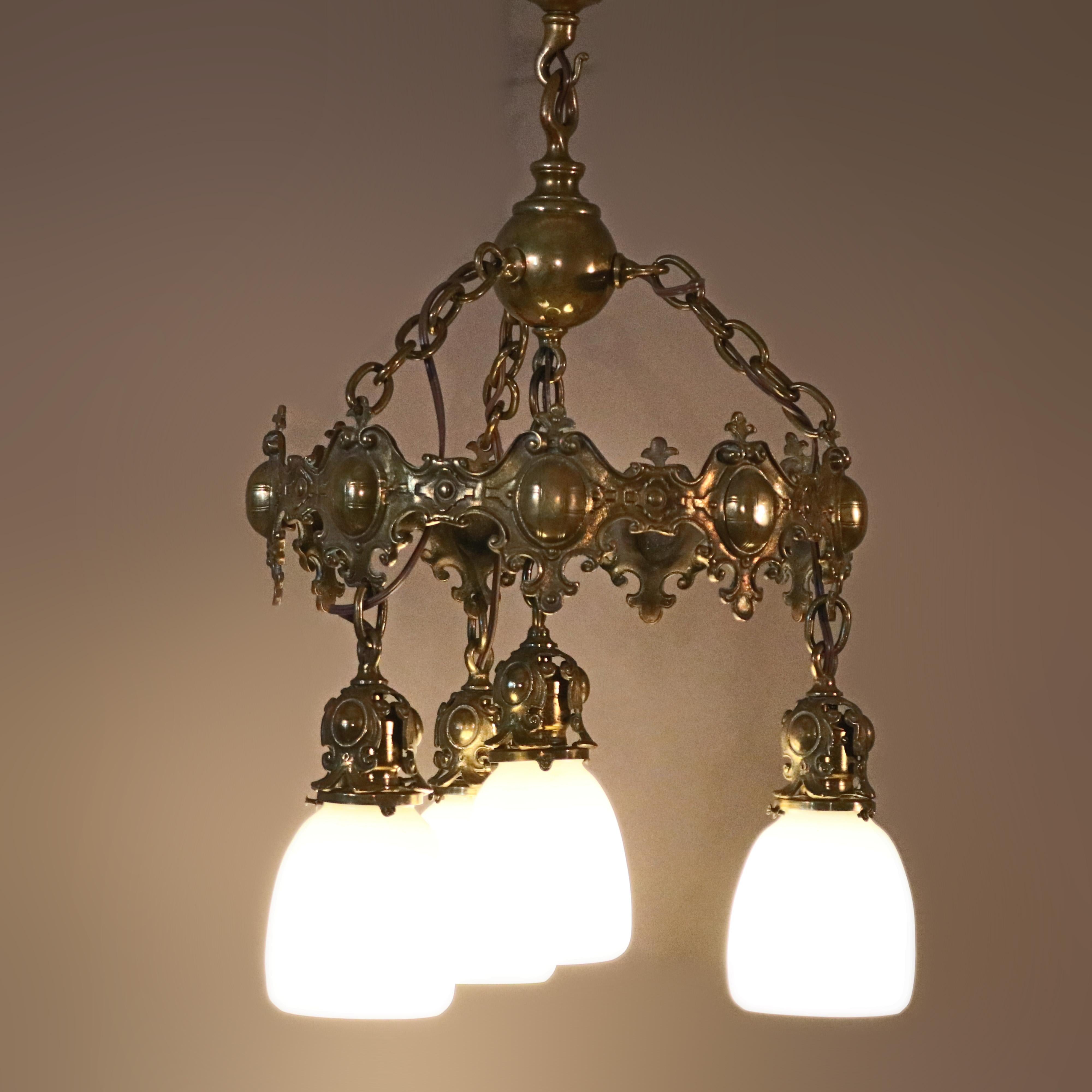 An antique Arts & Crafts Mission chandelier offers shield and foliate cast bronze frame with four drop lights having Steuben calcite shades, Gothic elements, 20th century.

Measures: 25.5