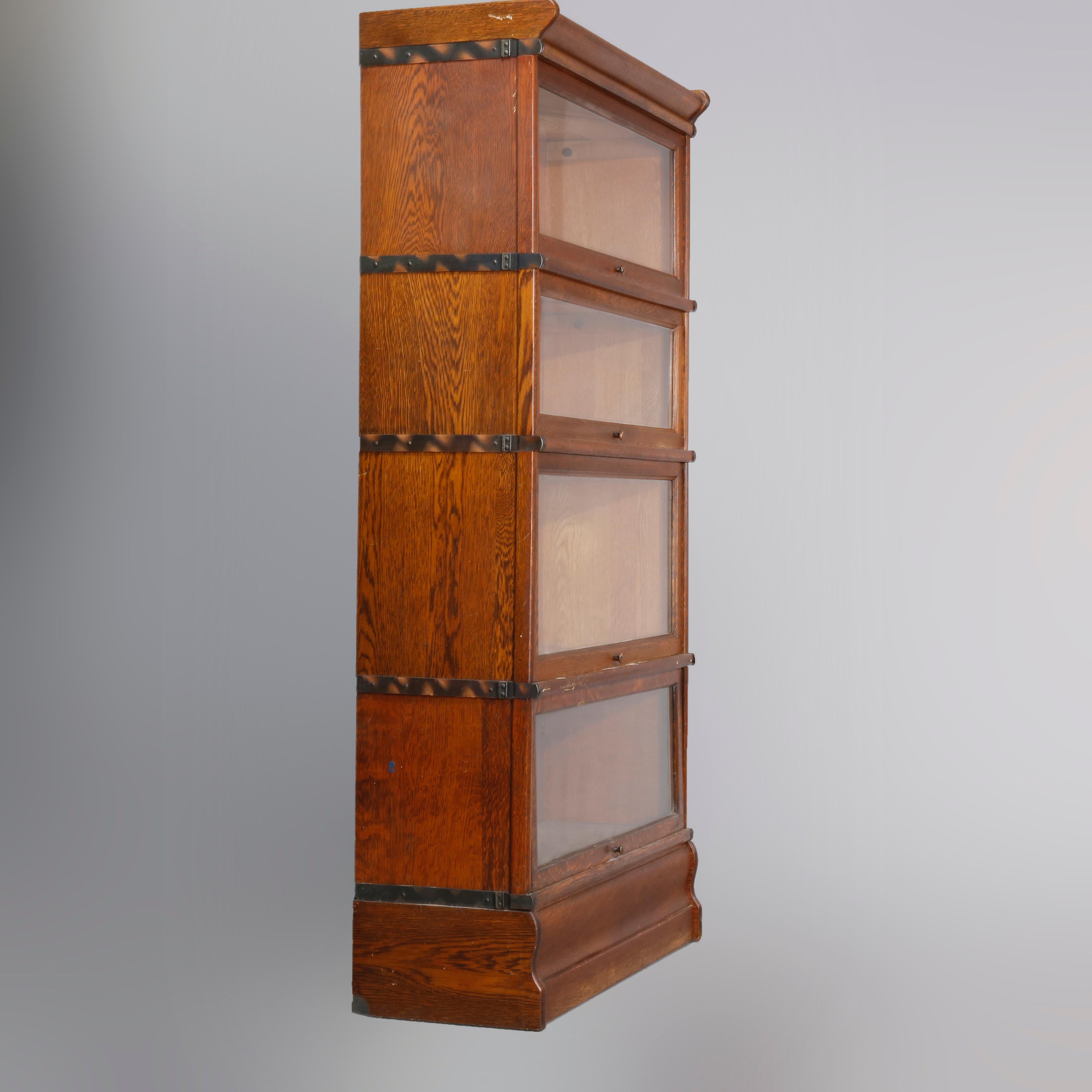 An Arts & Crafts sectional barrister bookcase in the manner of Globe-Wernicke, offers quarter sawn oak construction with four stacks each having a pull-down glass door on shaped base surmounted by removable crown, circa 1920

Measures: 60