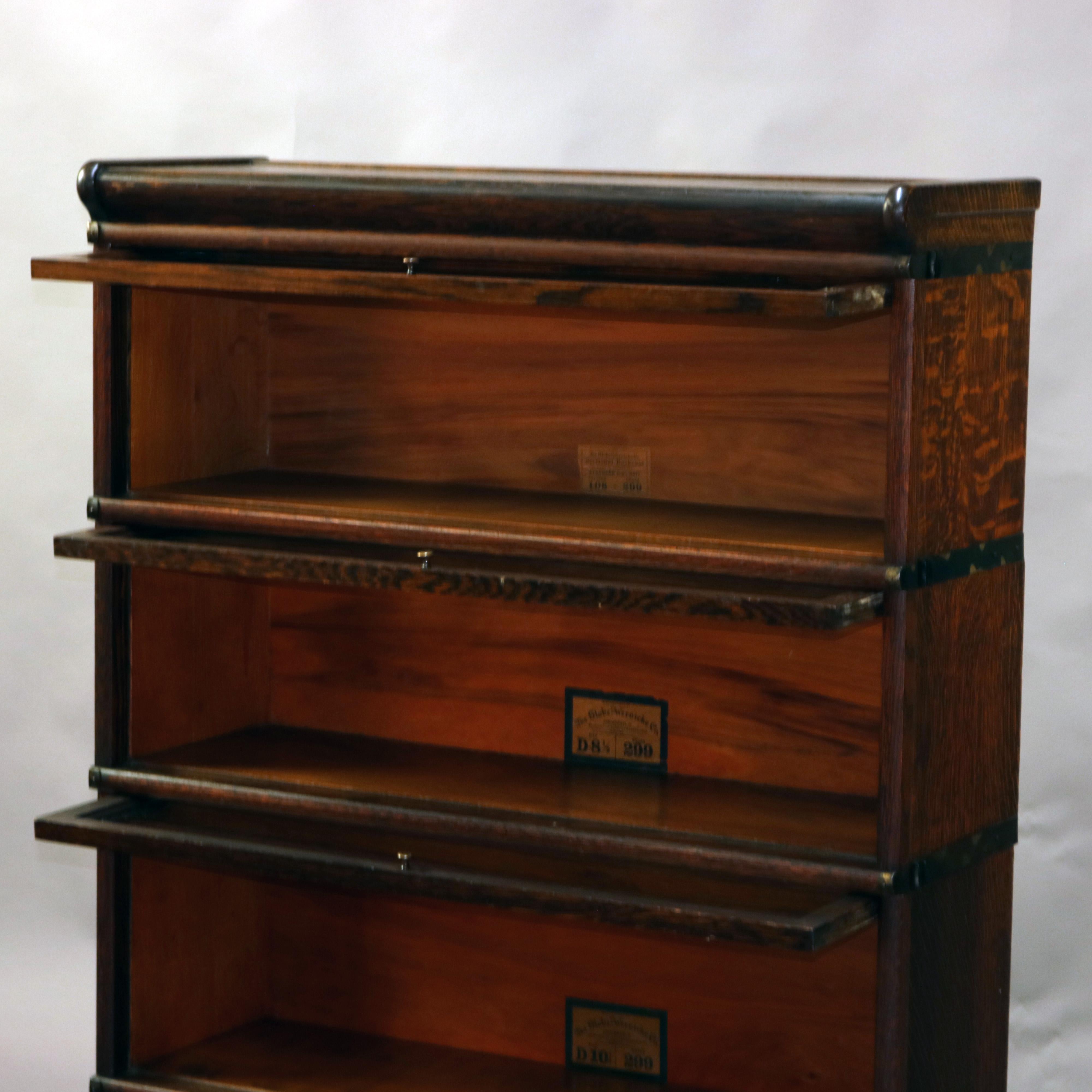 An antique Arts & Crafts barrister bookcase by Globe Wernicke offers oak construction with four stacks, base and crown, slide out glass doors, original labels as photographed, circa 1920

Measures: 58