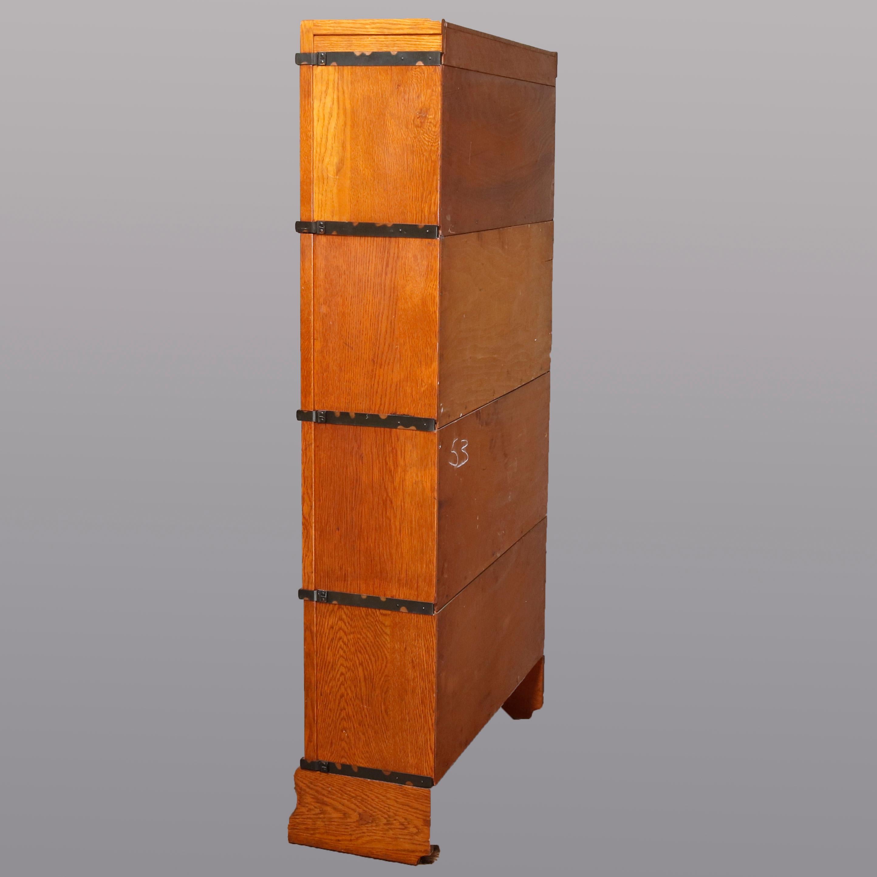 An Arts & Crafts sectional barrister bookcase by Globe-Wernicke Pattern 110, Grade 198, offers quarter sawn oak construction with four stacks each having a pull-down glass door on shaped base surmounted by removable crown, circa 1920

Measures -