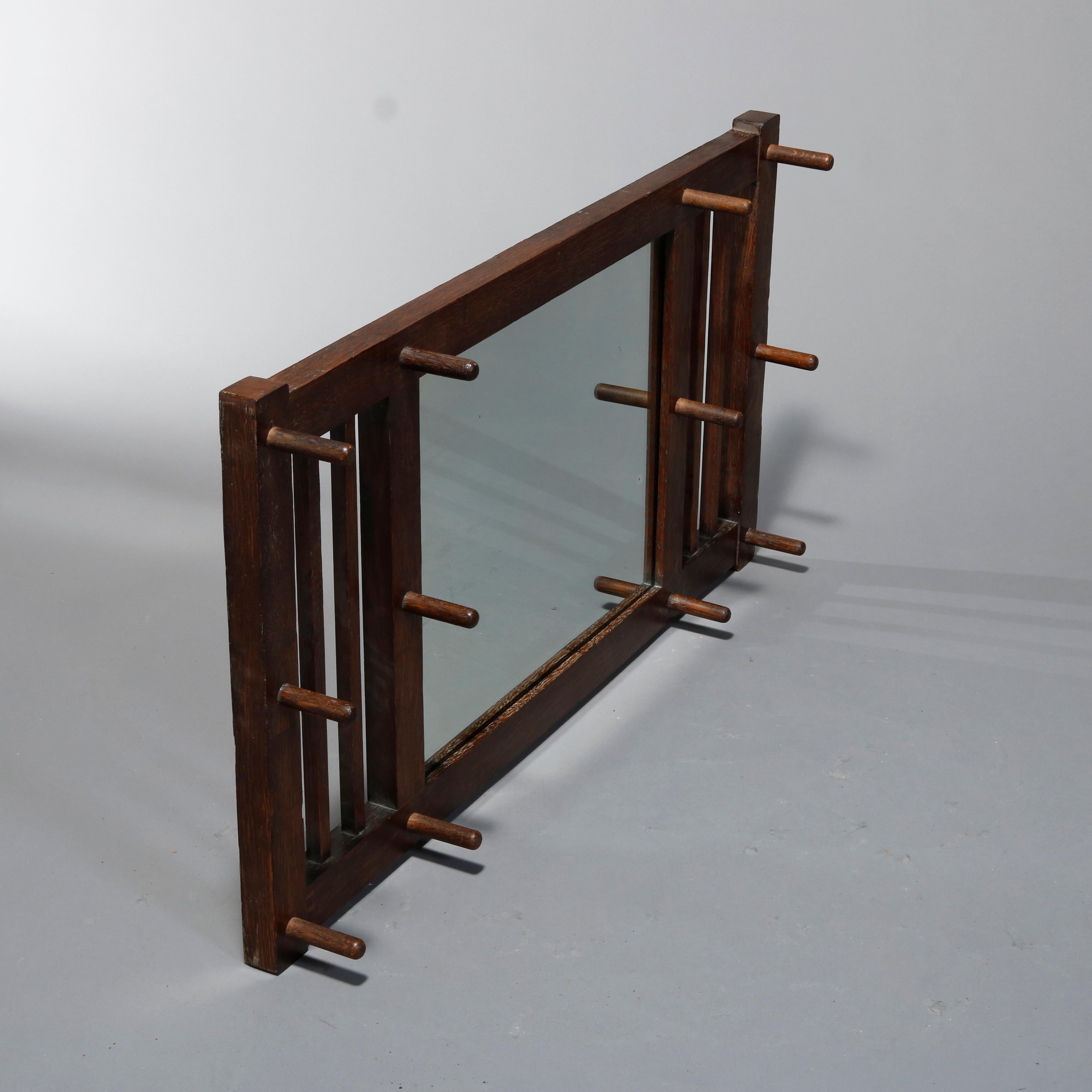 An antique Arts & Crafts Mission hat rack wall mirror by Stickley Bros. offers quarter sawn oak construction with central mirror having flaking slat sides with hat hangers, en verso stenciled 513, c1910

Measures: 24.75