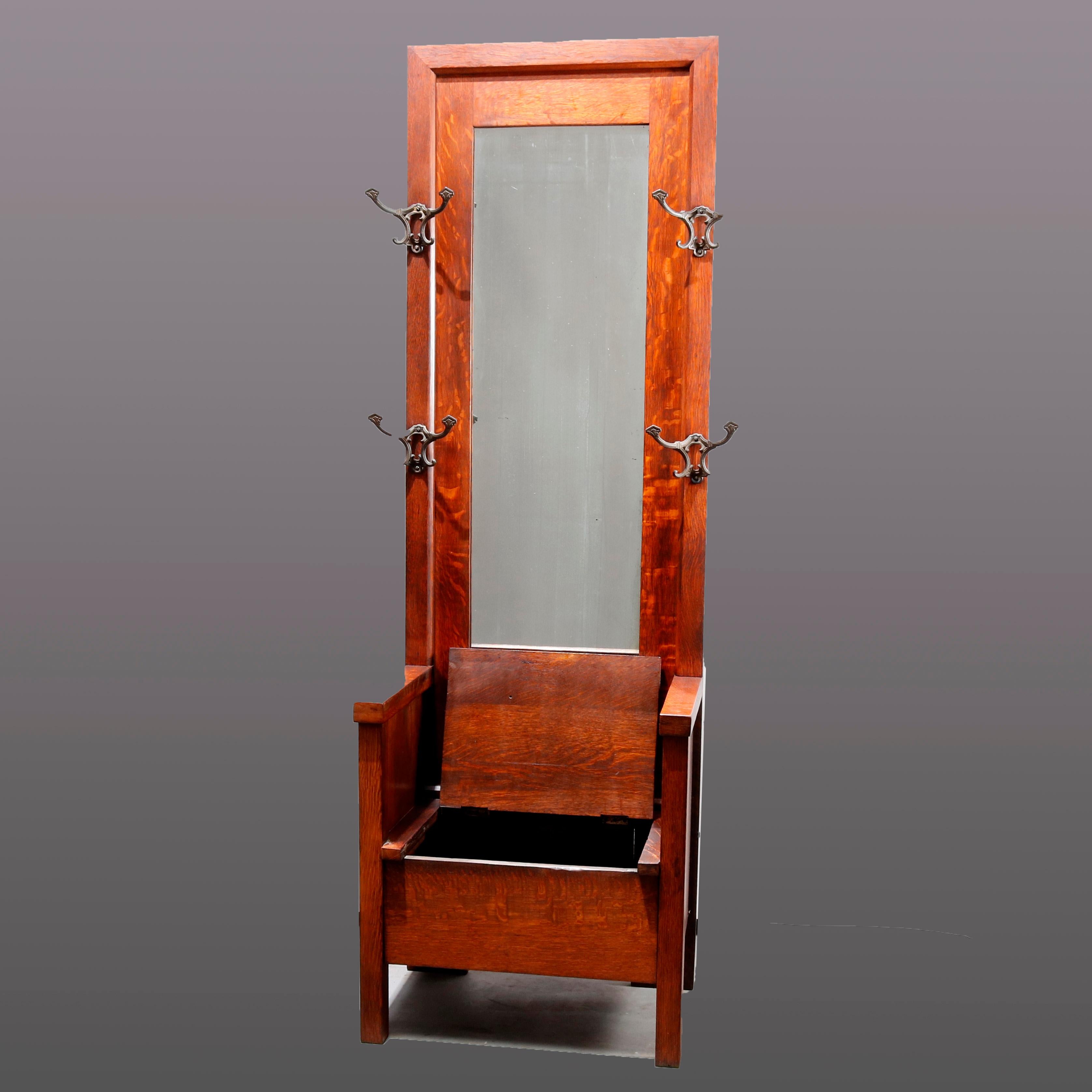 An antique Arts & Crafts Stickley School hall seat by Stickley School offers cube form with lift top seat having storage compartment and solid arm surmounted by tall mirror flanked by cast bronze apparel hooks, circa 1910

Measures: 73