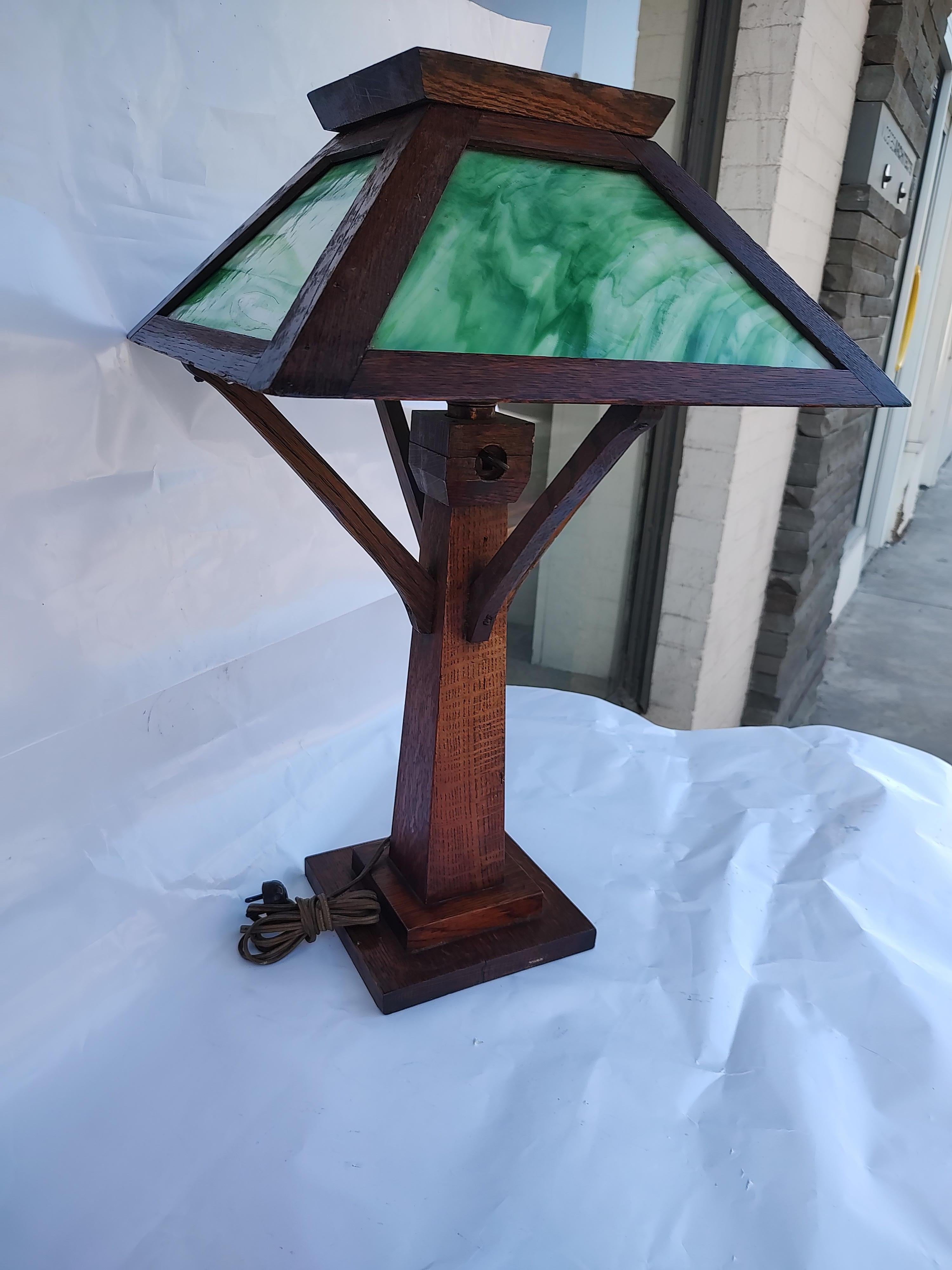 Fabulous Mission Oak Arts & Crafts table lamp with green/white slag glass panels. Quarter sawn oak and hand crafted. Tapered base with 4 supporting arms that hold the shade in place. In excellent vintage condition with minimal wear. This item can be