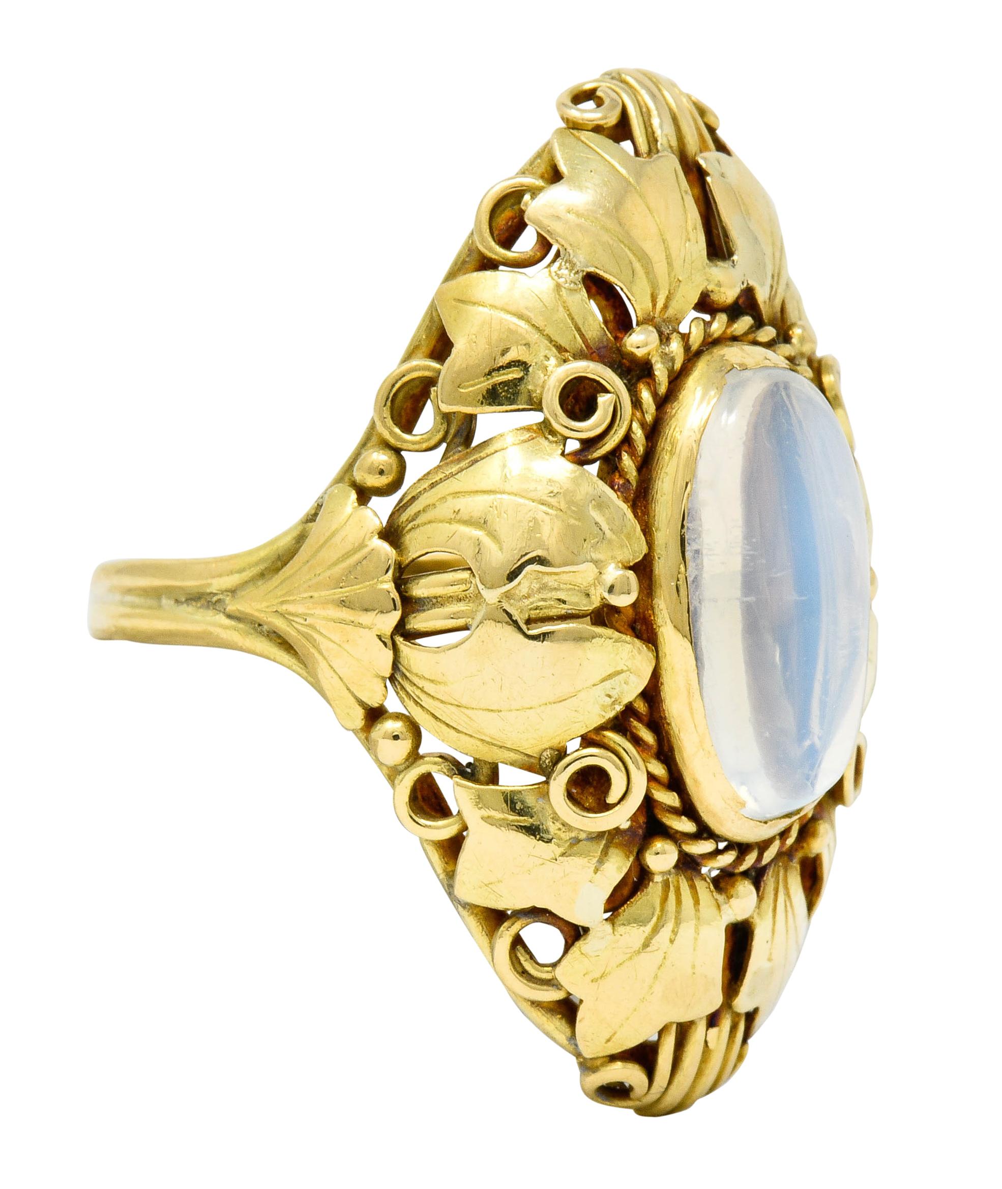 Designed as an elongated navette form comprised of layered ivy and ginkgo leaves

Accented throughout by gold bead and scrolled wire details

Centering an oval moonstone cabochon measuring approximately 12.5 x 6.6 mm, translucent with strong billowy