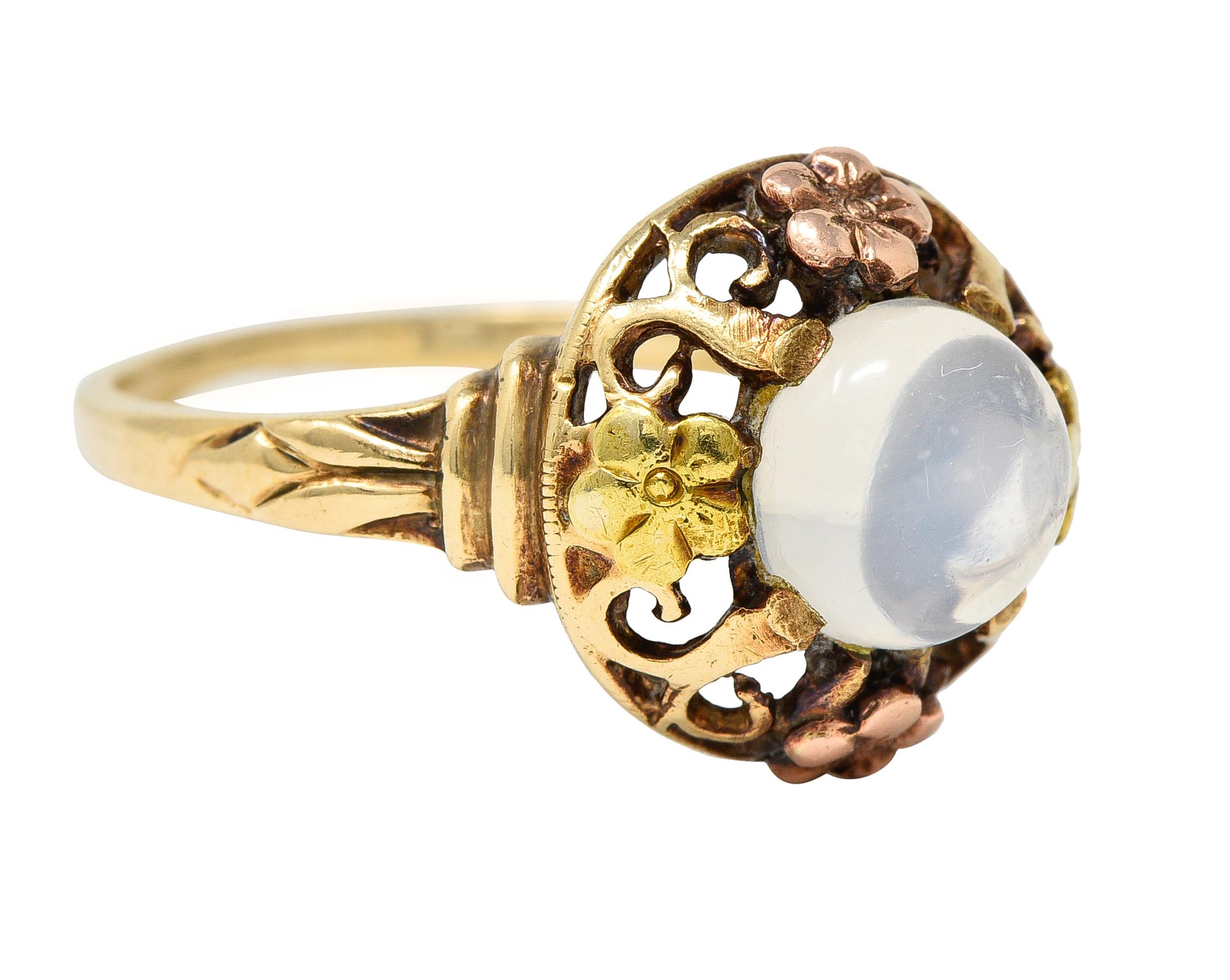 Zentrierung eines 7,0 mm großen runden Mondstein-Cabochons - farbloser Körper mit weißer Adulareszenz
Mit Peitschenmotivzacken besetzt, die sich im Muster mit erhabenen Blumenmotiven abwechseln
Rose und grünes Gold in Farbe mit gerillten