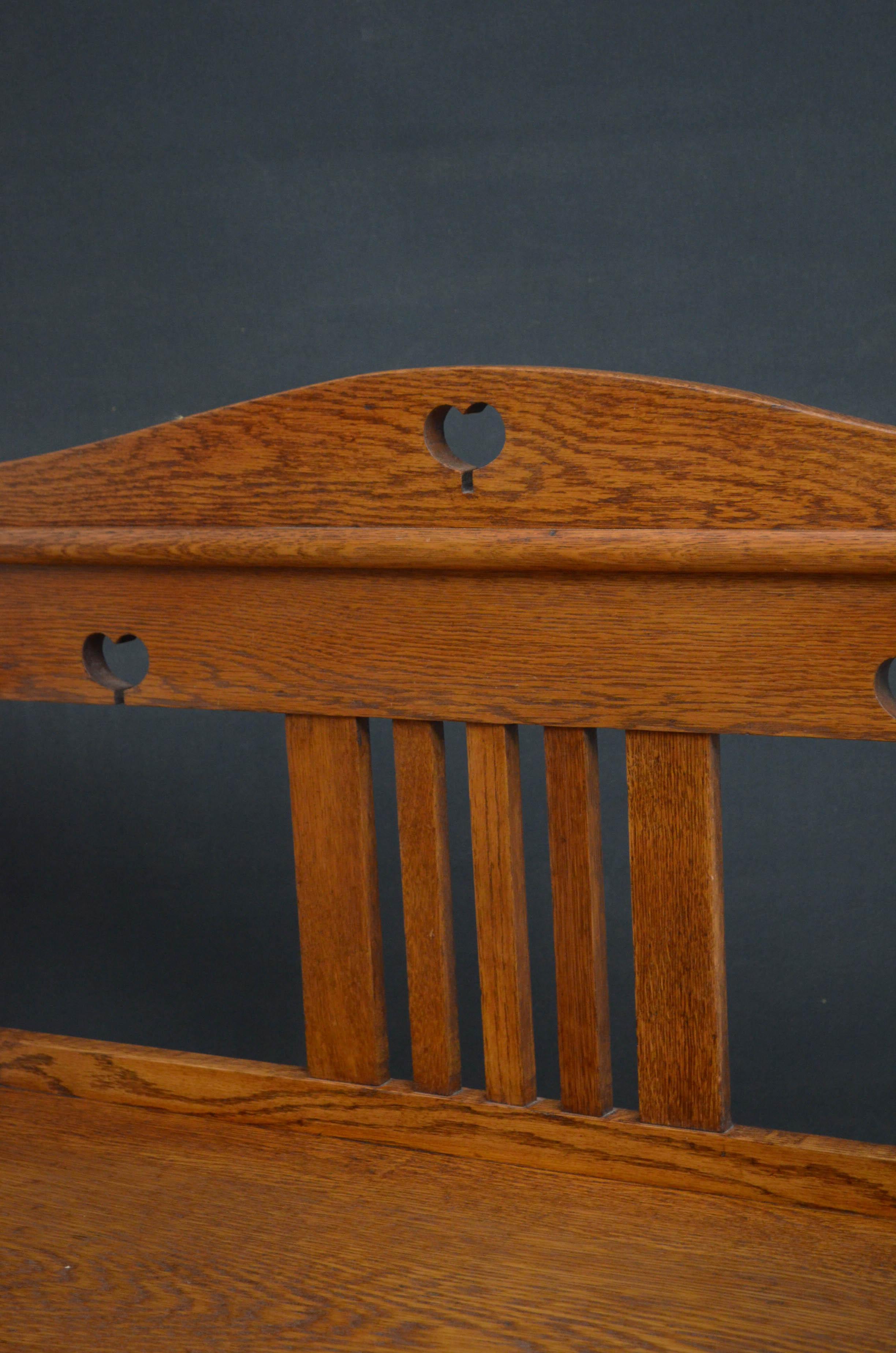 Sn4677, a stylish Arts & Crafts, solid oak hall bench, having shaped top rail and generous seat flanked by pad arms, standing on robust supports with carved decoration to front and united by moulded stretchers. This Arts & Crafts hall seat has been