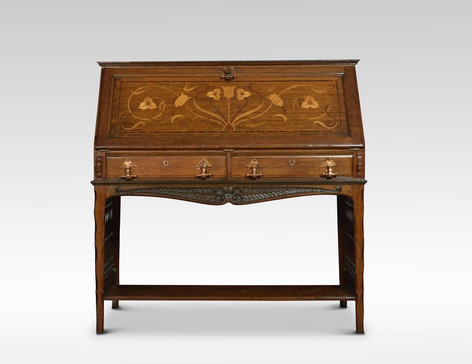 Arts & Crafts oak bureau, the rectangular top above inlaid fall front. Opening to reveal a fully fitted interior having inset black tooled leather writing surface. Over two drawers with scroll copper handles. The base section with carved apron