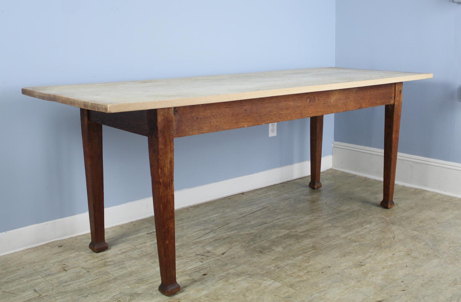 A simple farm table with a clean bleached top. Stylized feet and interesting color contrast between the top and the base, both oak. 24.5 inch apron height is good for knees and there are 57.5 inches between the legs on the long side.