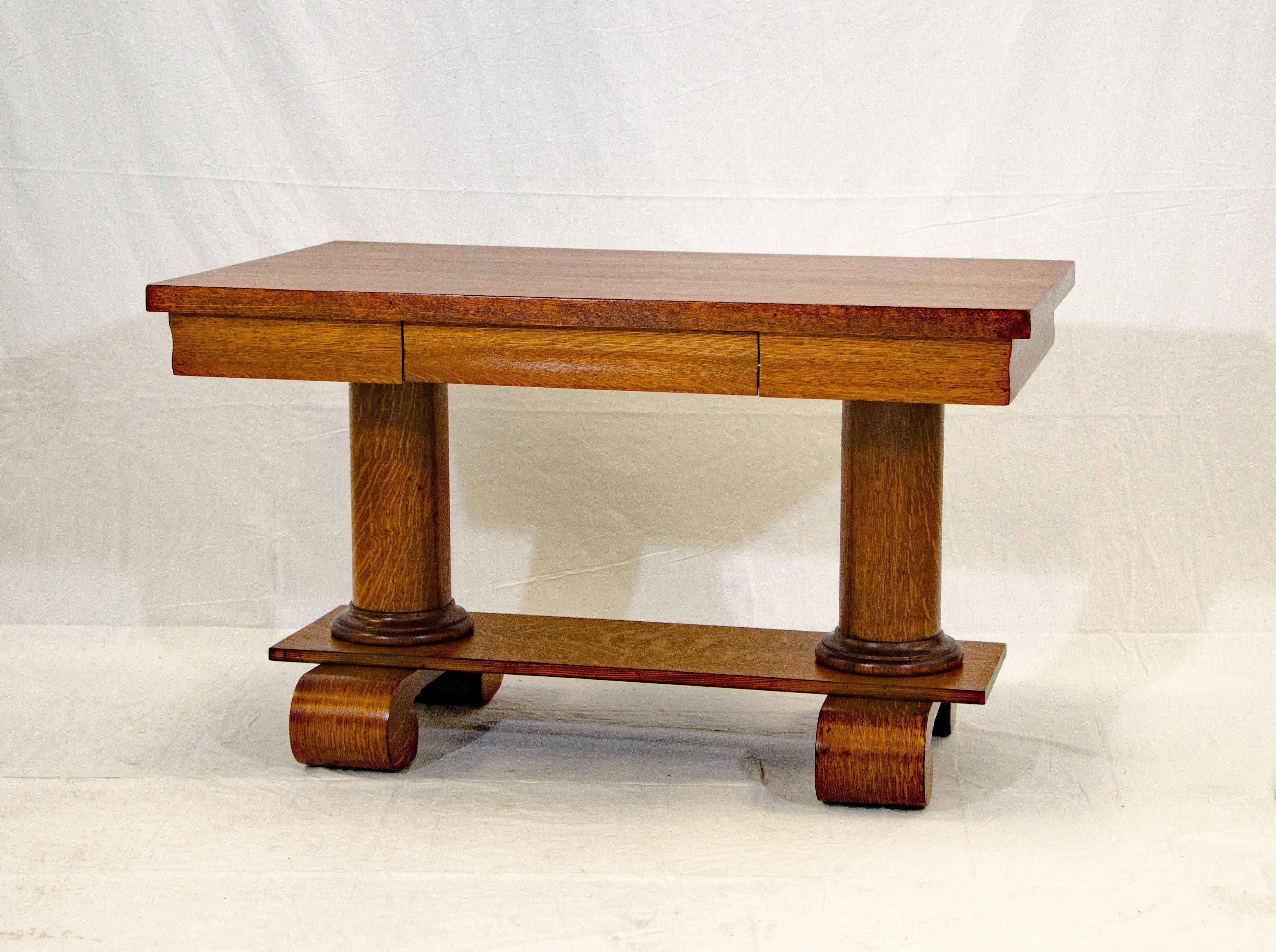 Vintage turn of the century Art & Crafts quarter sawn oak library table with round pedestals between the top writing surface and the base. The one storage drawer pulls out in the center of the top with an interior height of 2 1/2