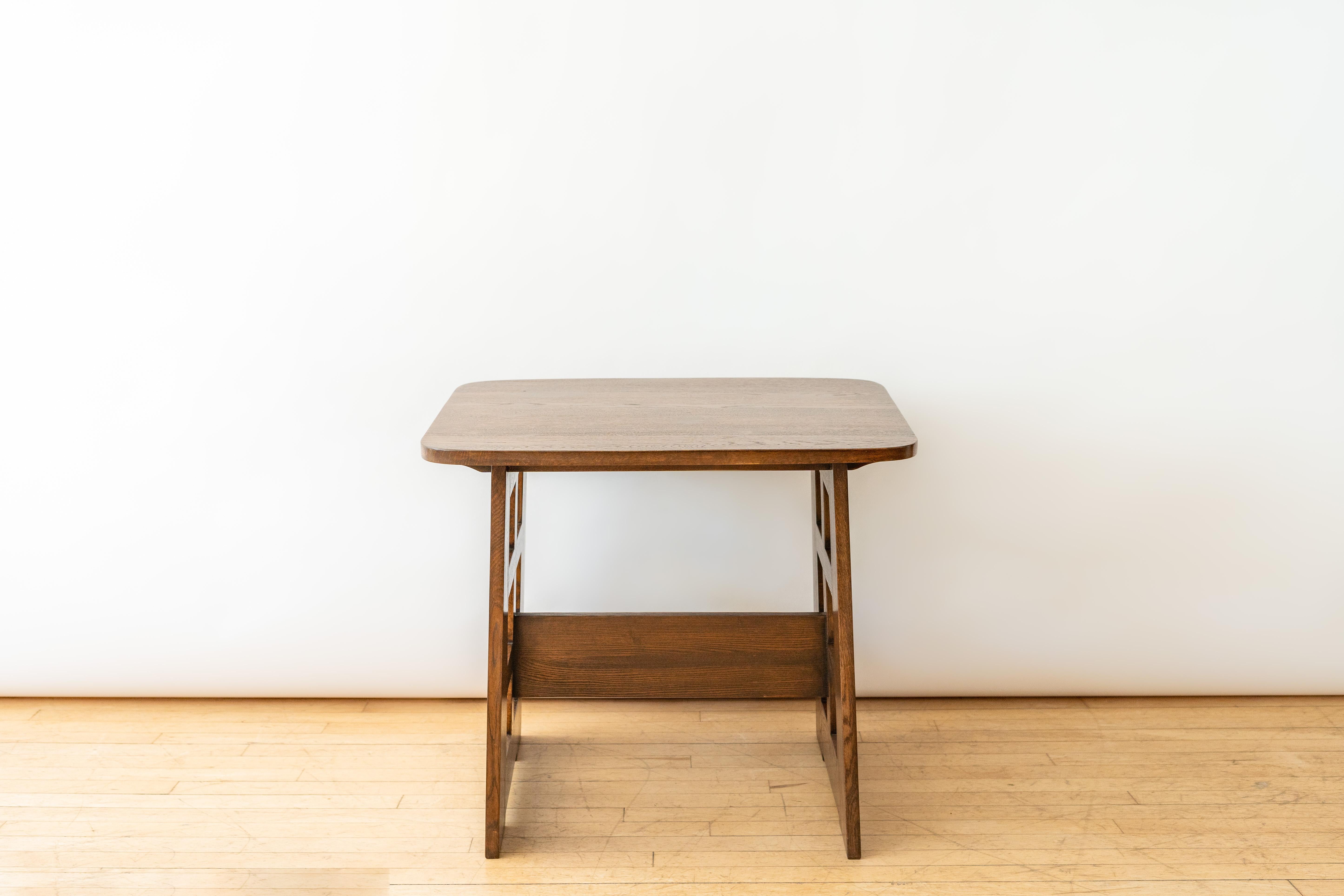 USA, ca. 1930s. A versatile library or hall table after the No. 140 occasional table by Limbert. Features solid oak construction with flared rectangular top supported geometric cut-out legs. During frequent trips to Europe in the early 1900s,