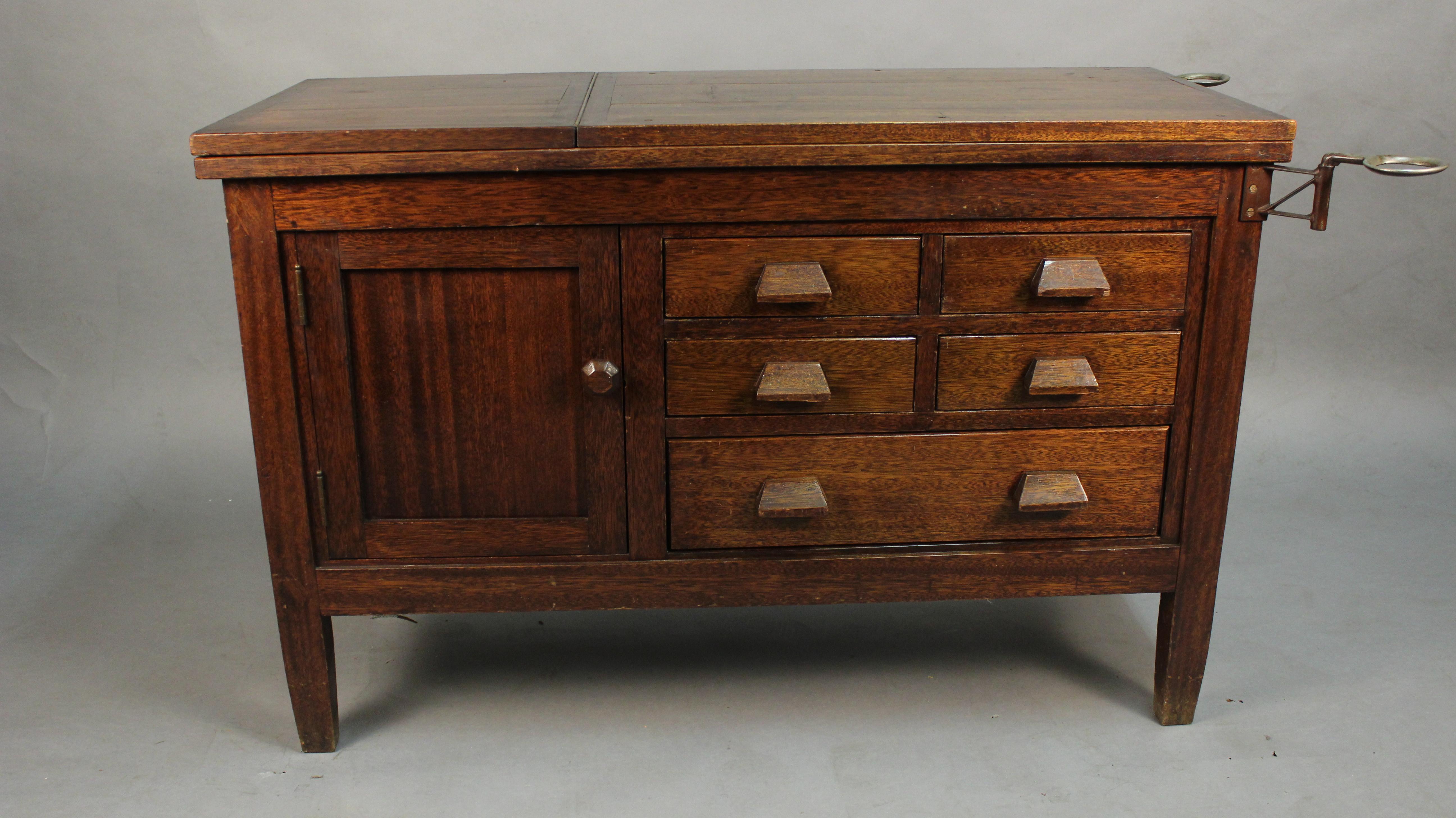 Examining table, drawers and doors on both sides, circa 1910. Top tilts up. Measures: 31.5